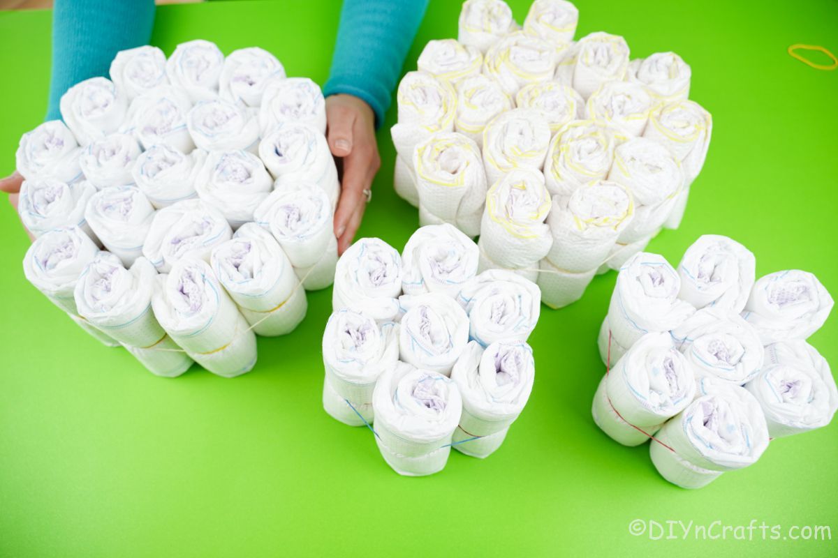 four bundles of diapers in various sizes on green table