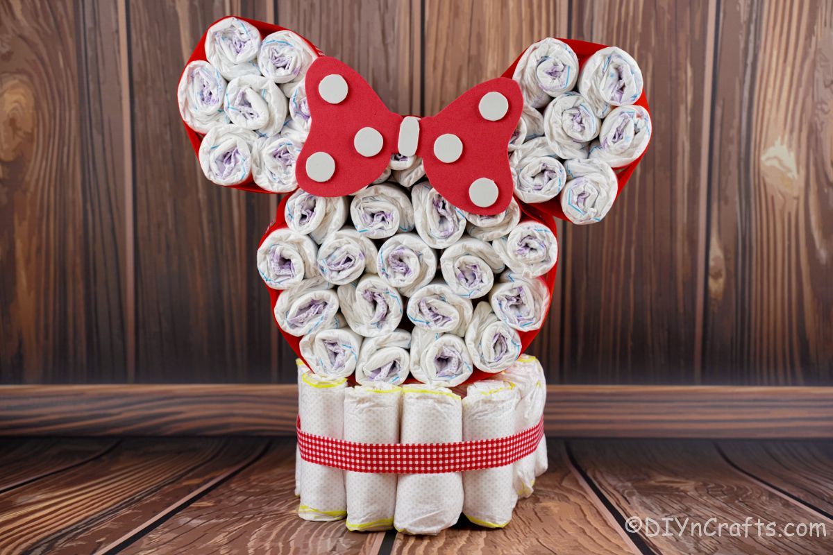 Disney red and white Minnie head diaper cake in front of wood wall