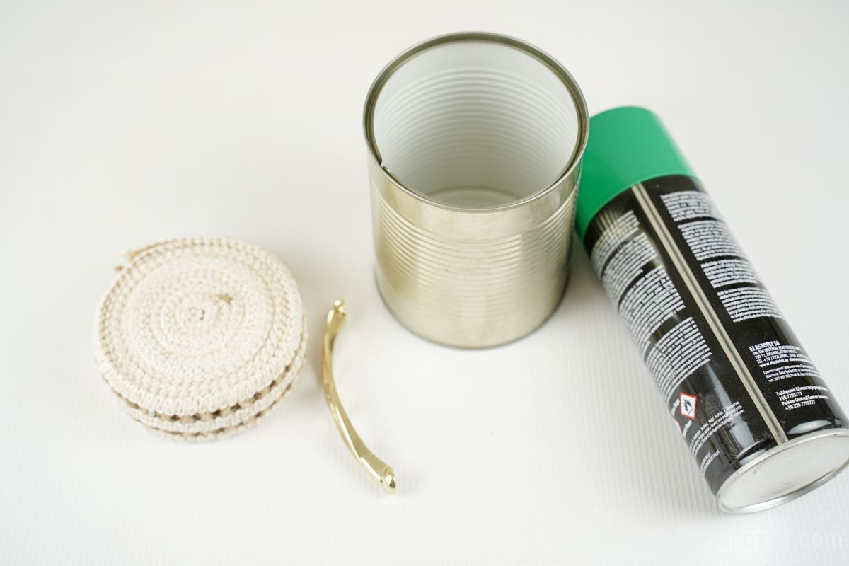 tin can ribbon gold handle and green pant on white table