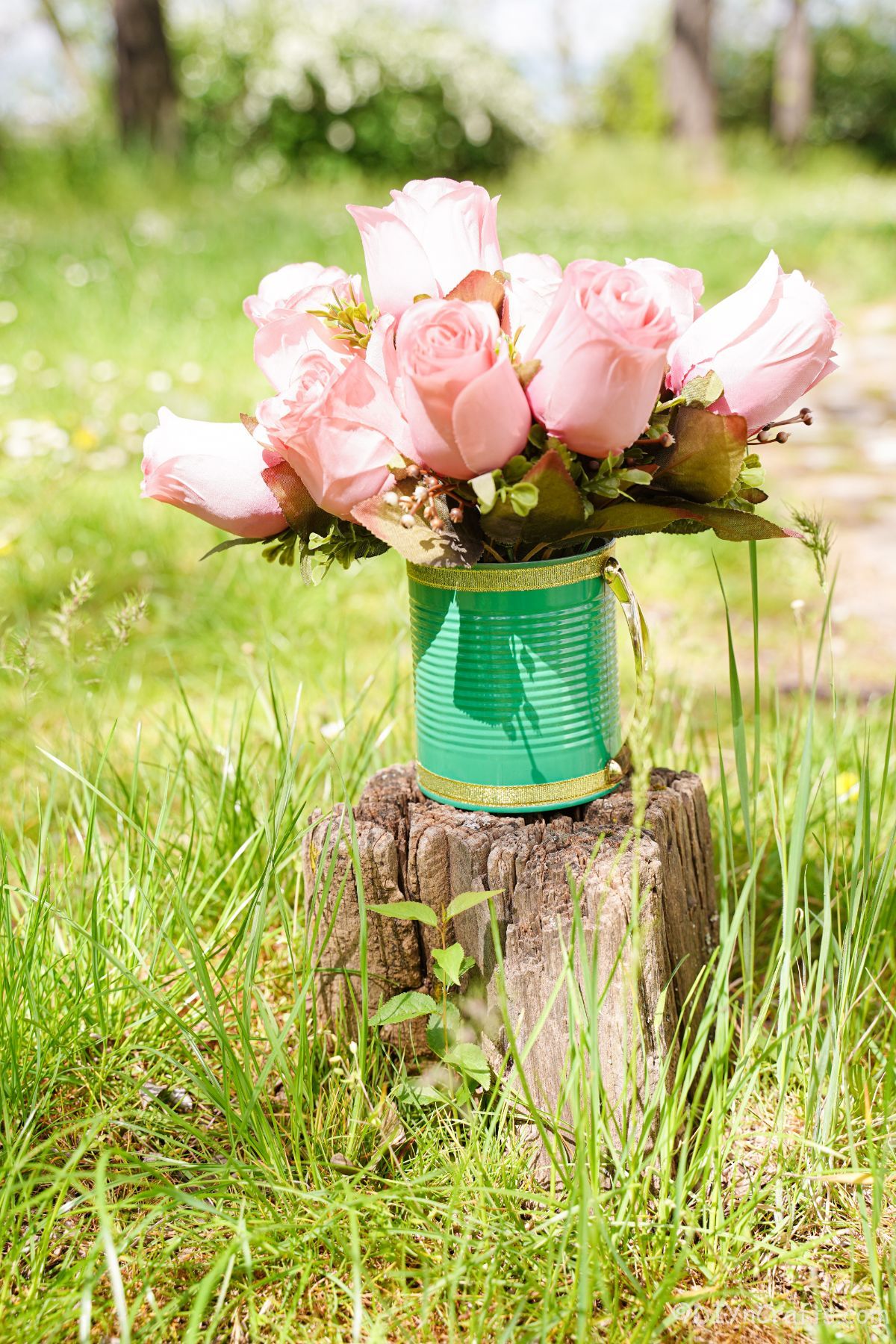 pink roses inside light green and gold tin can on stump