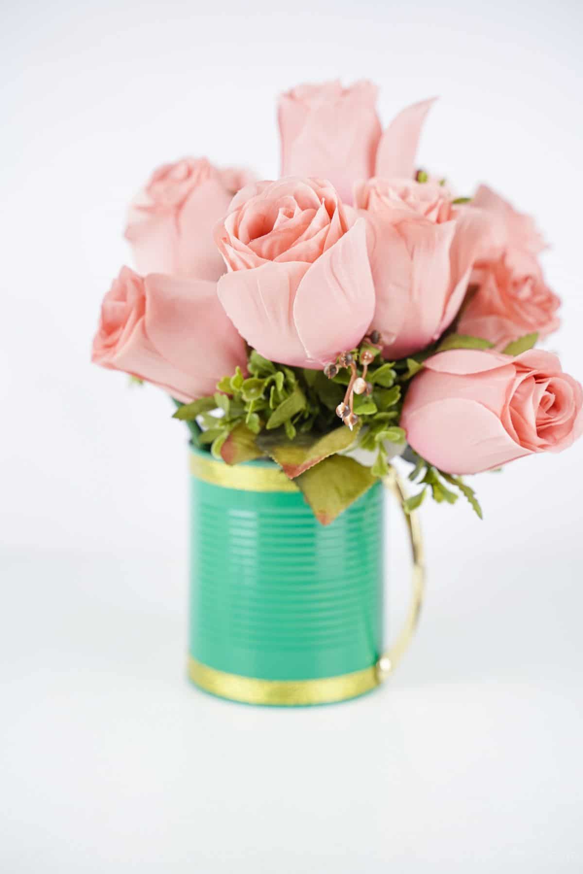 pink roses in light green and gold mug on white table