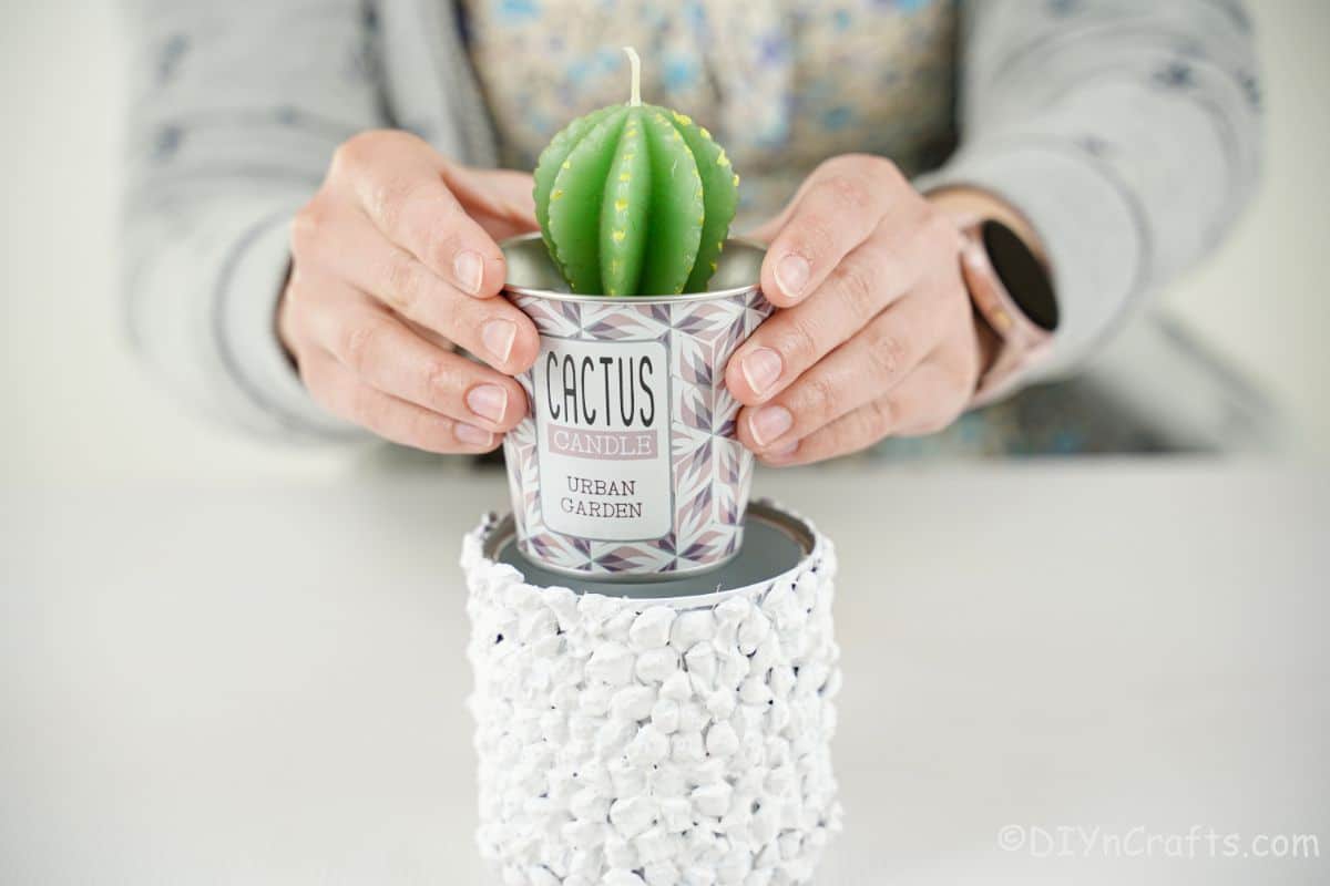 hands putting candle inside planter
