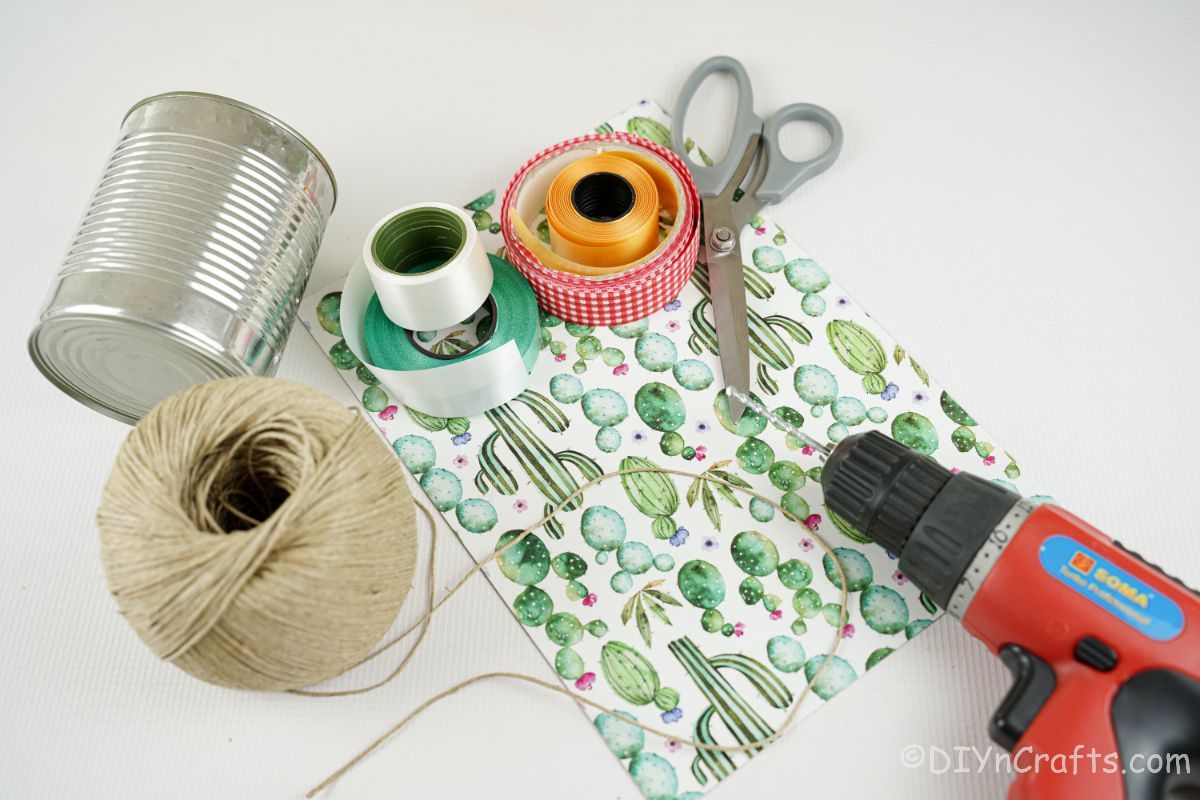 tin can twine paper and ribbon on white table with scissors and drill
