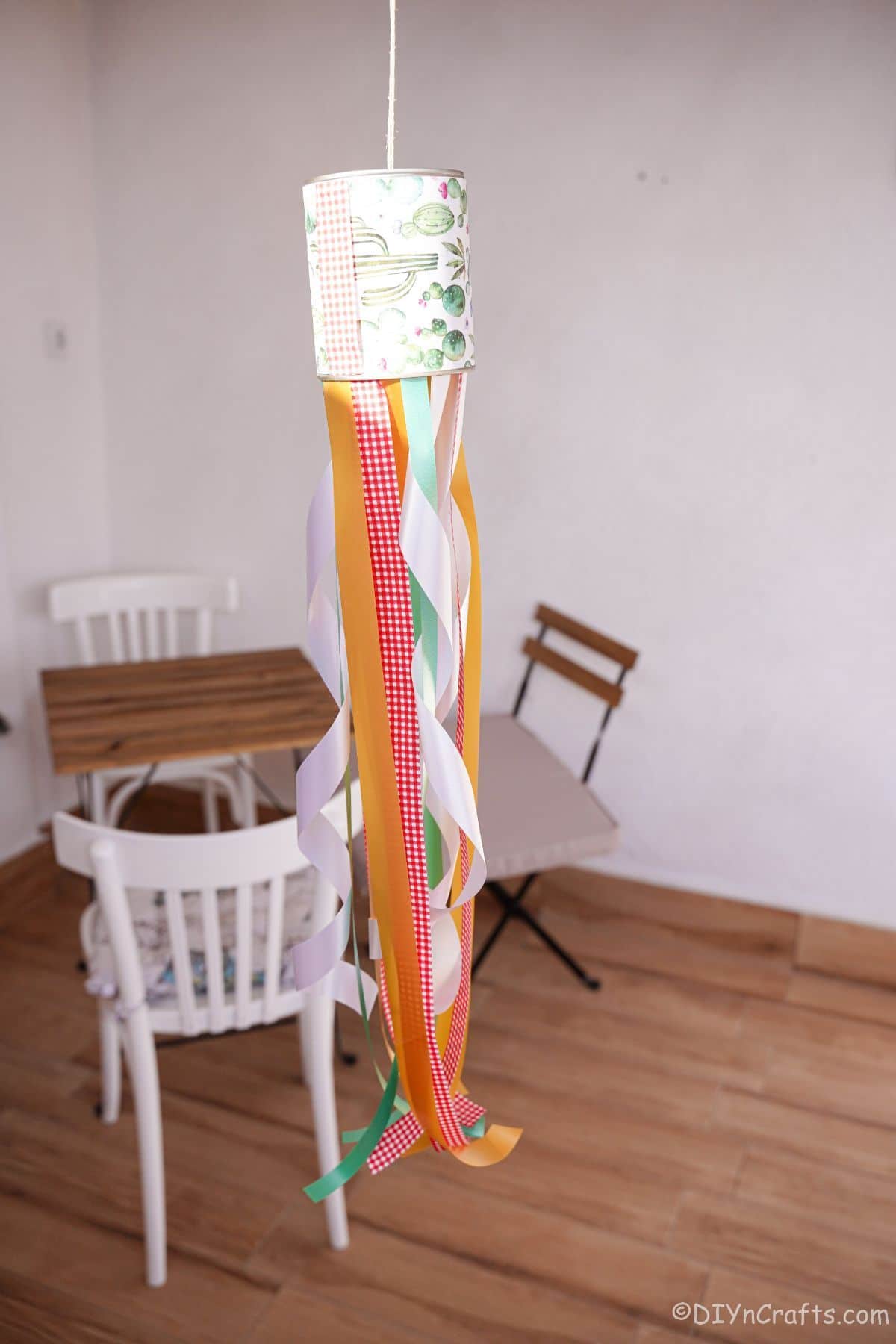 tin can windsock hanging in front of small table with white chairs