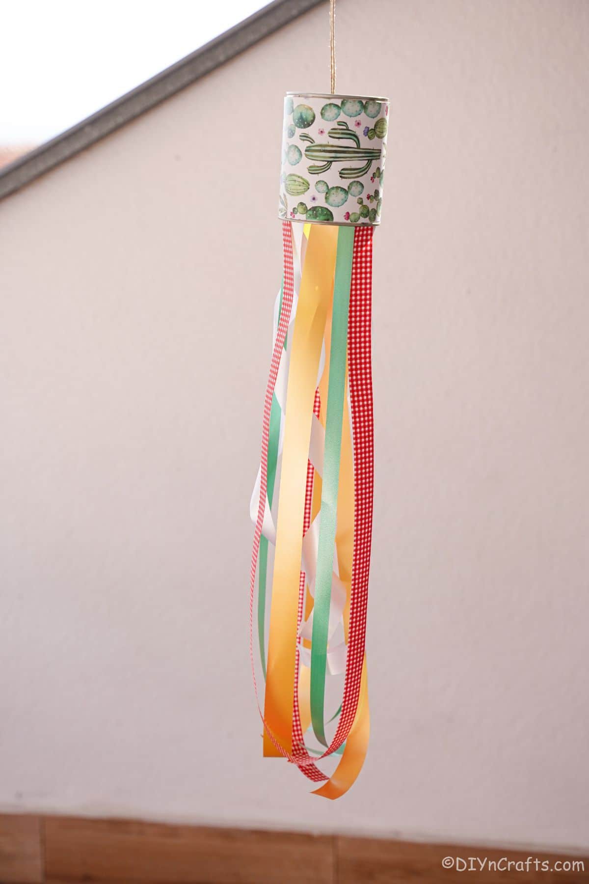 windsock made of cans and ribbons in front of a white wall