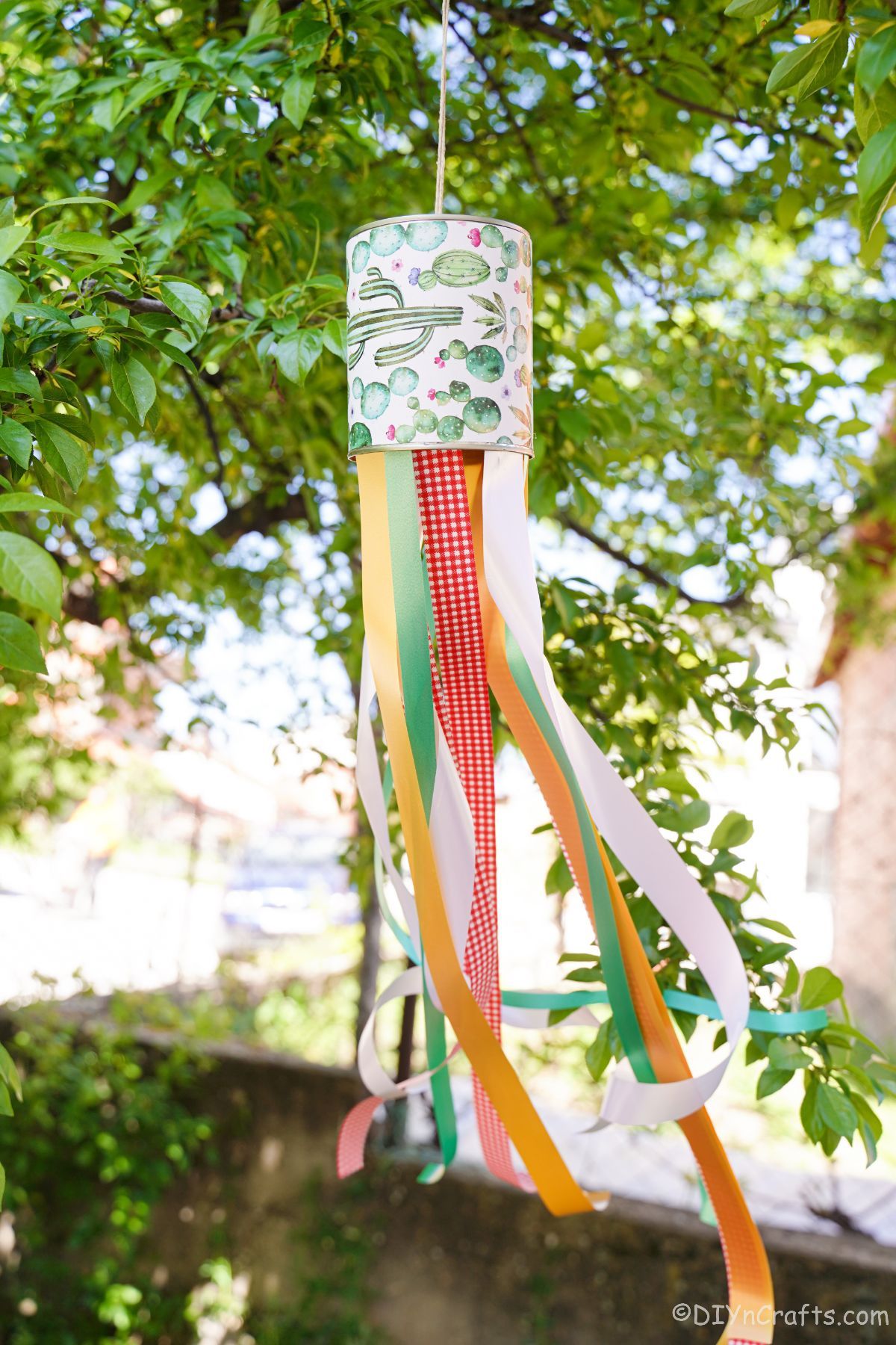 tree holding windsock made of tin can and ribbons