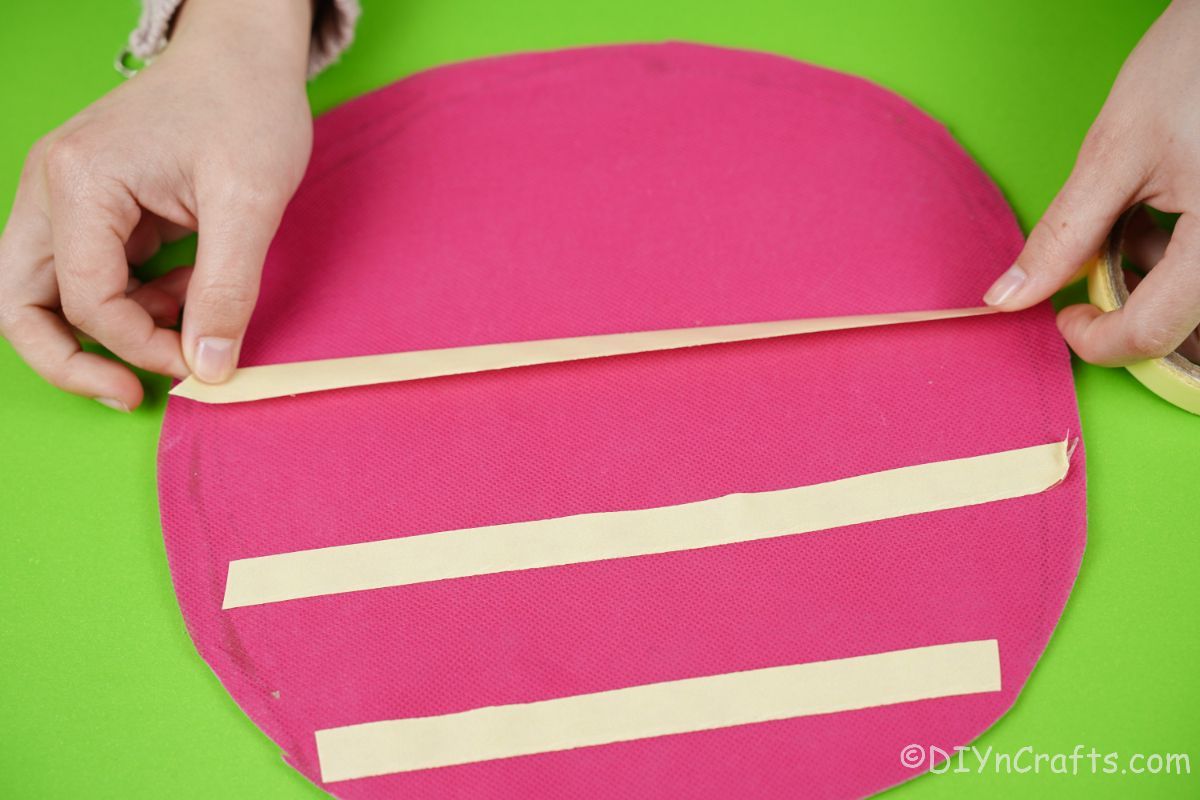 hand adding tape to pink diaper cake base