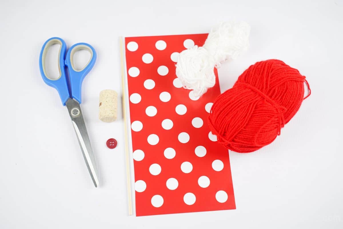 red and white paper with red yarn white yarn and blue scissors on white table