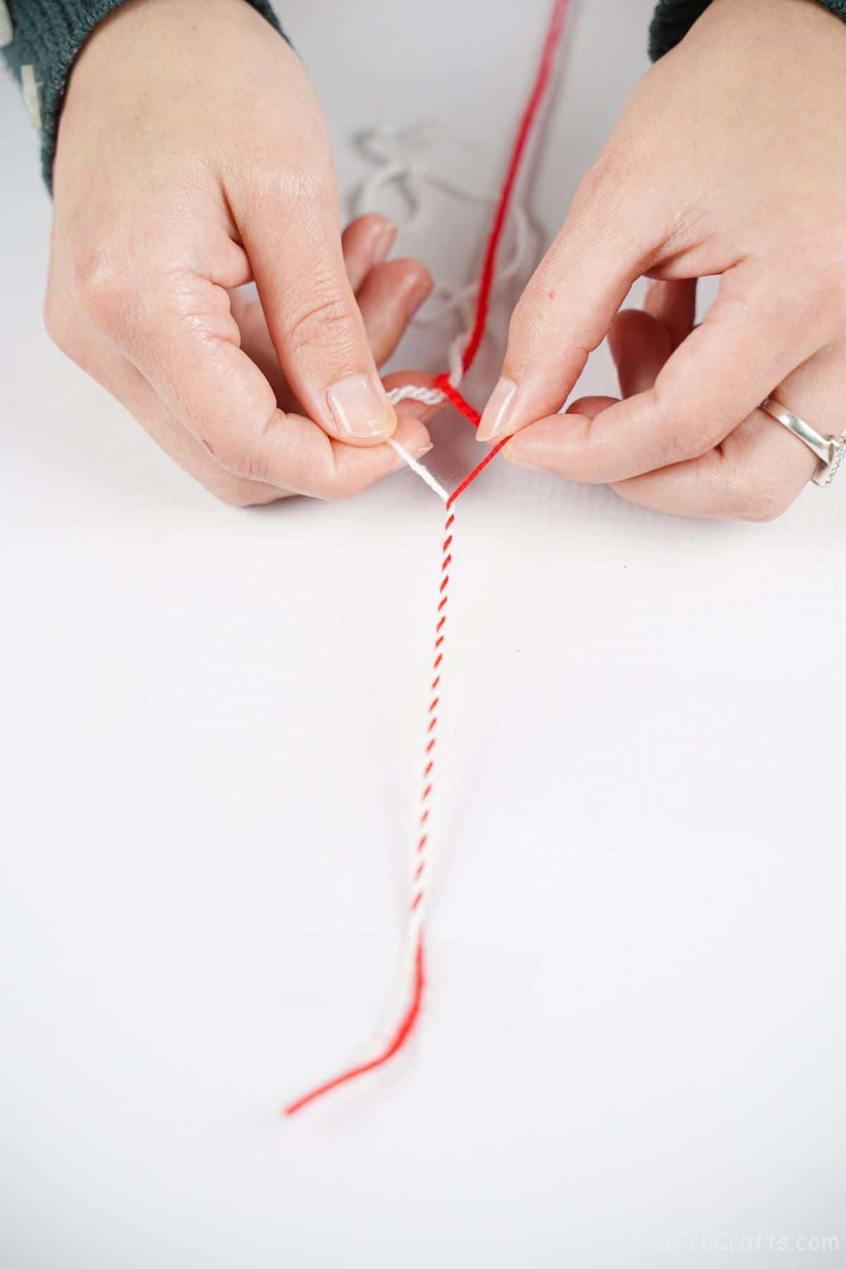 red and white yarn on table being twisted together