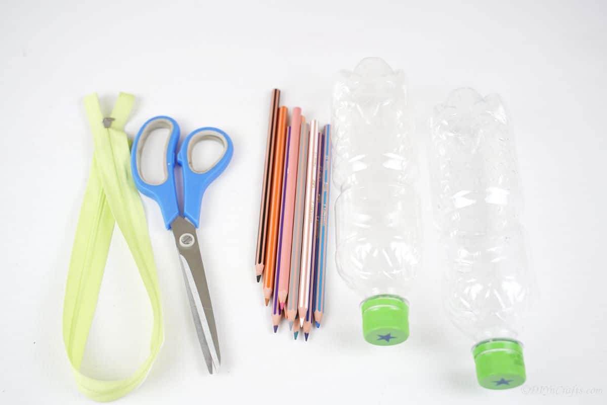 zipper scissors pencils and empty water bottles on white table