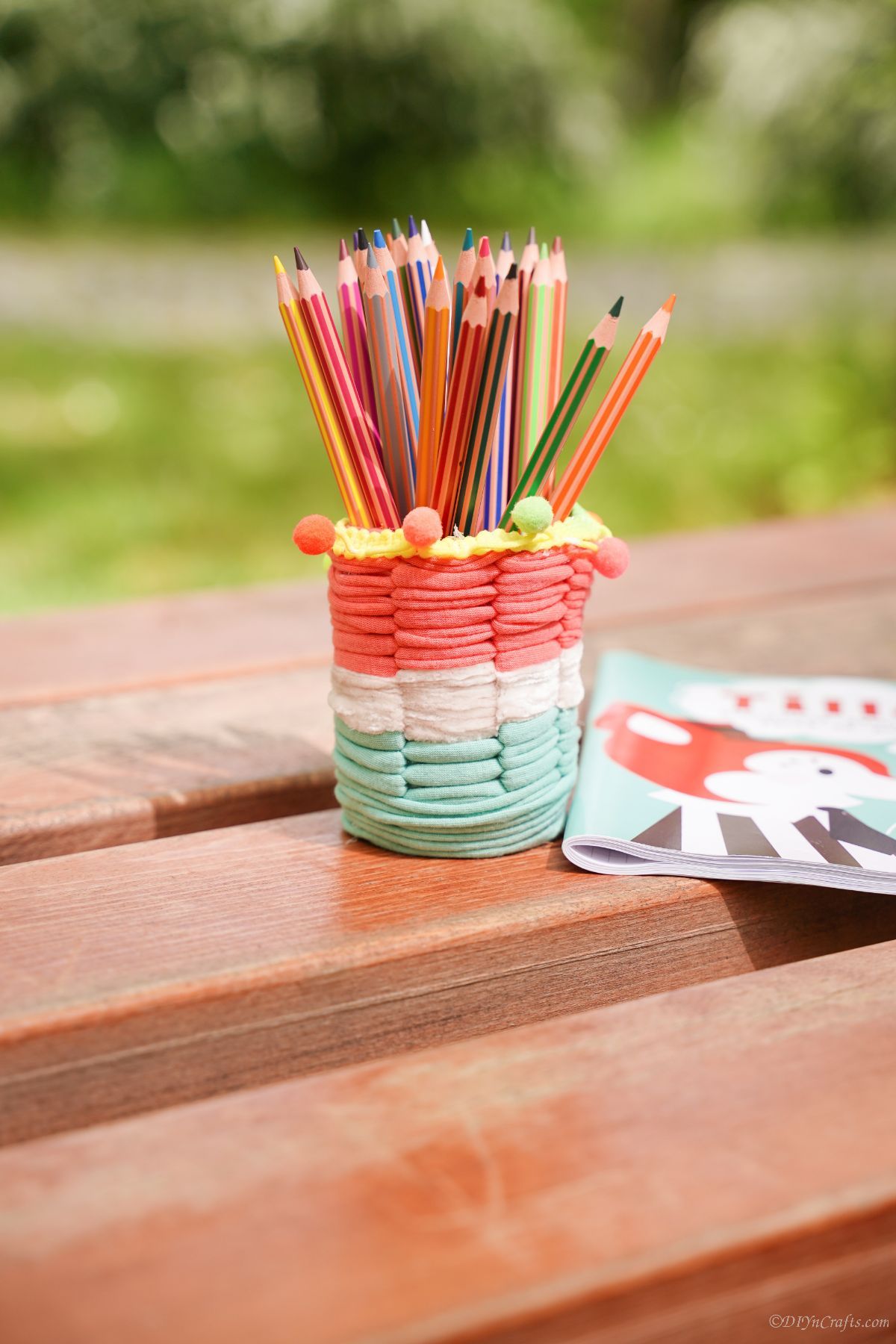 striped white green and pink covered pencil cup on picnic table