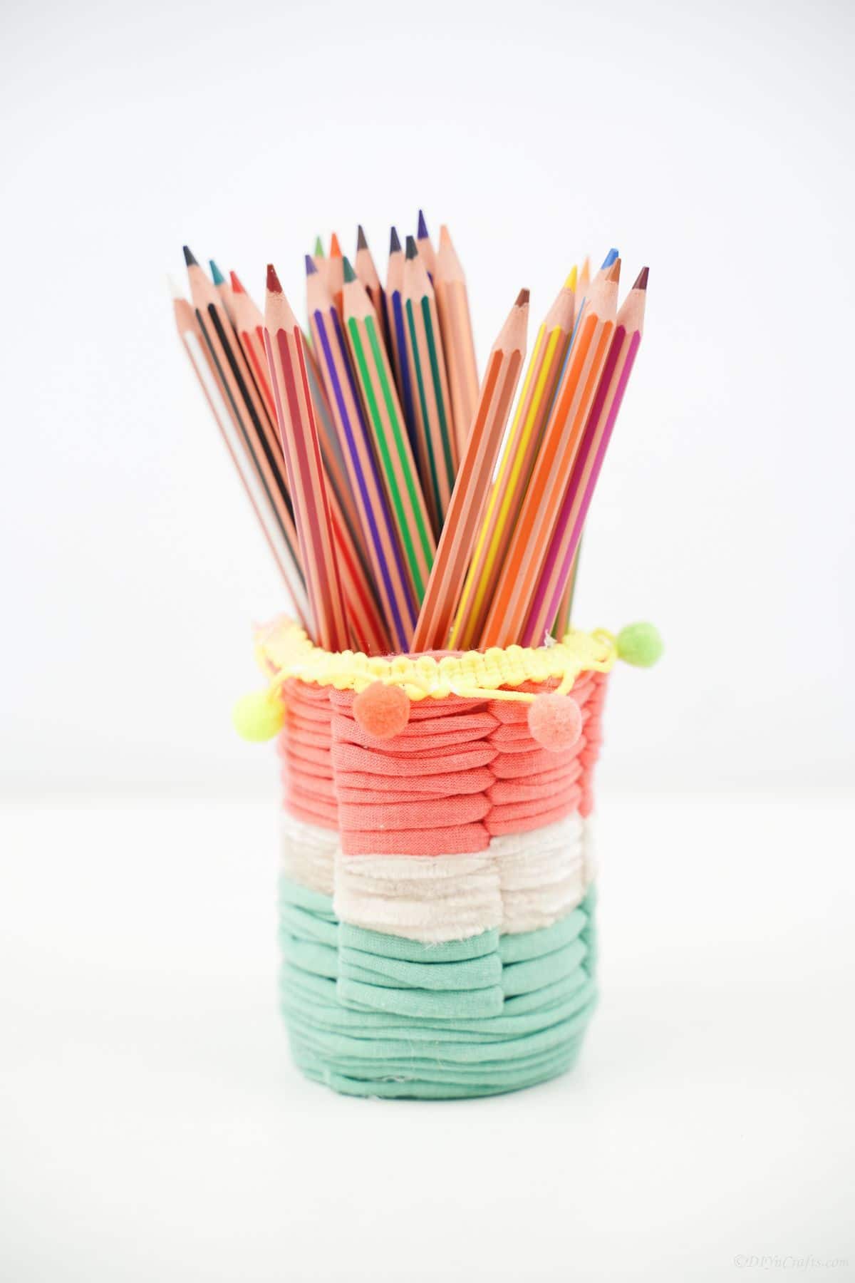 pink green and white yarn covered pencil holder on white table