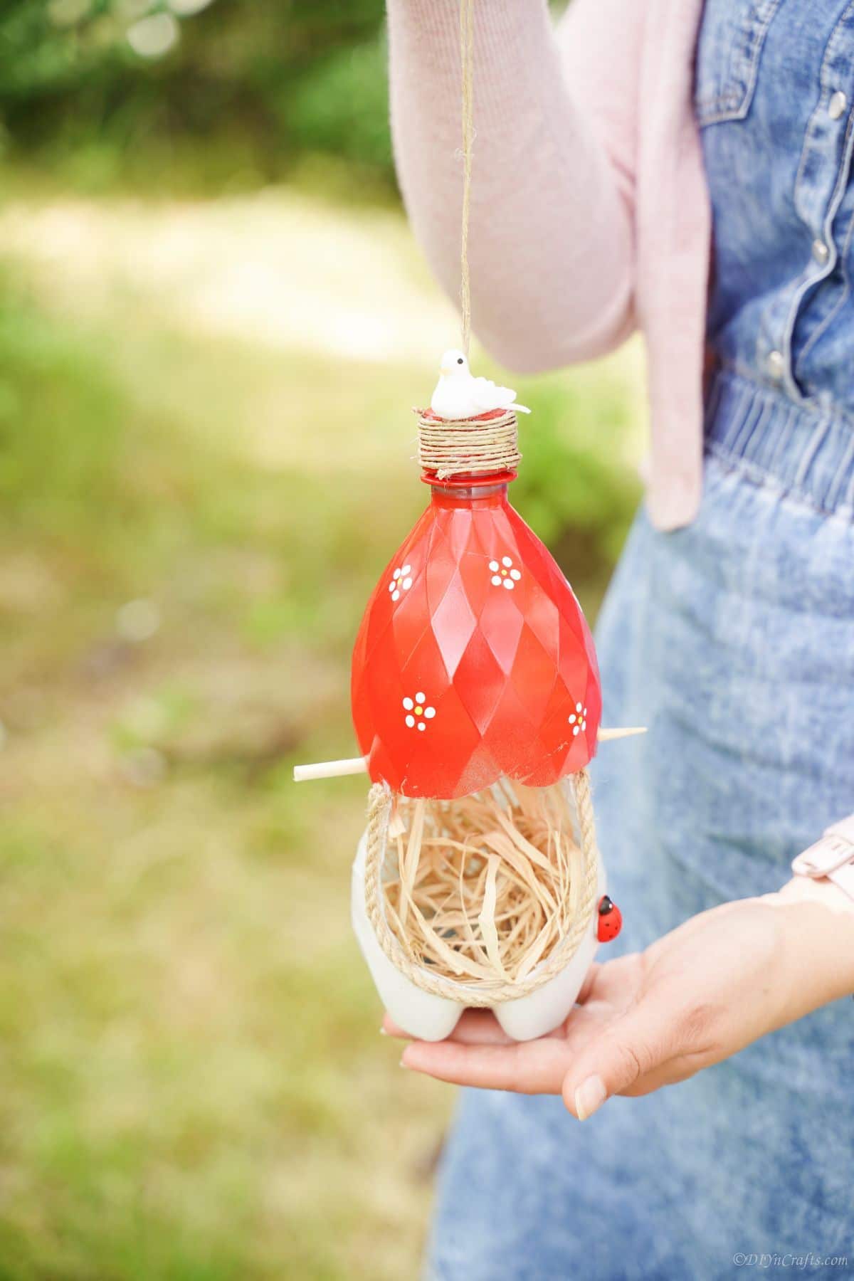 woman holding red and white bottle nest for birds