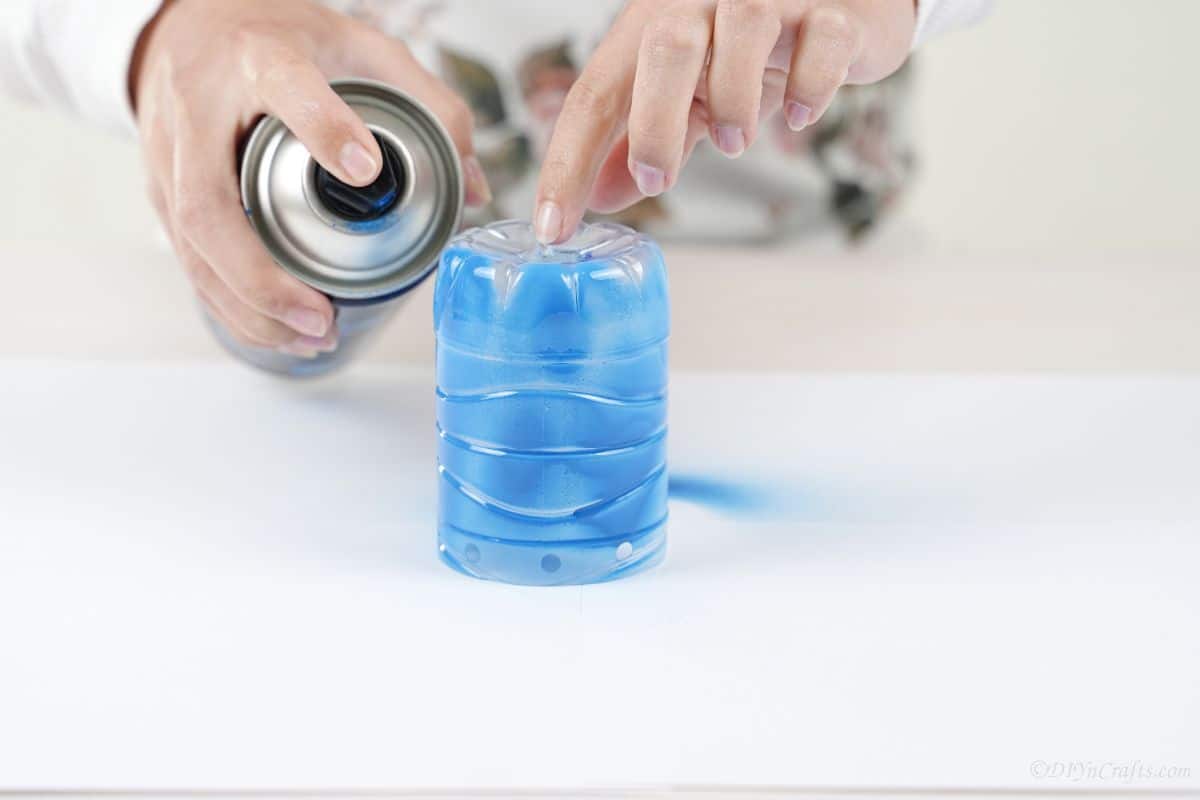plastic bottle being sprayed with blue paint