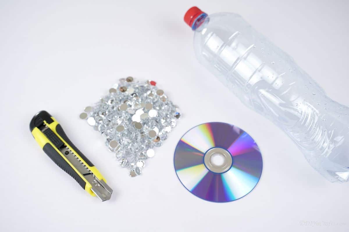 rhinestones CD and plastic bottle on white table with craft knife