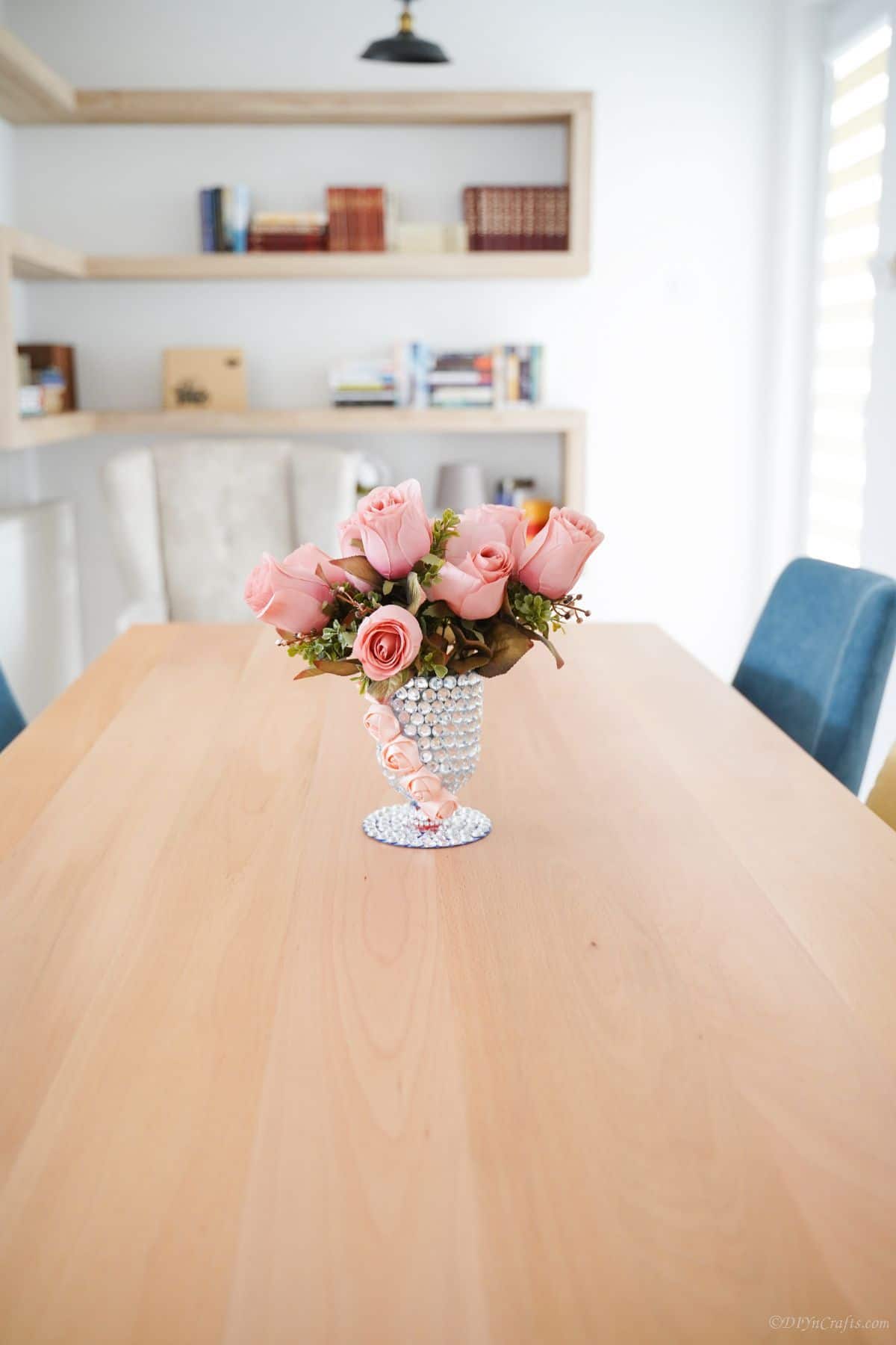 dining table with blue chairs and rhinestone vase of roses in center