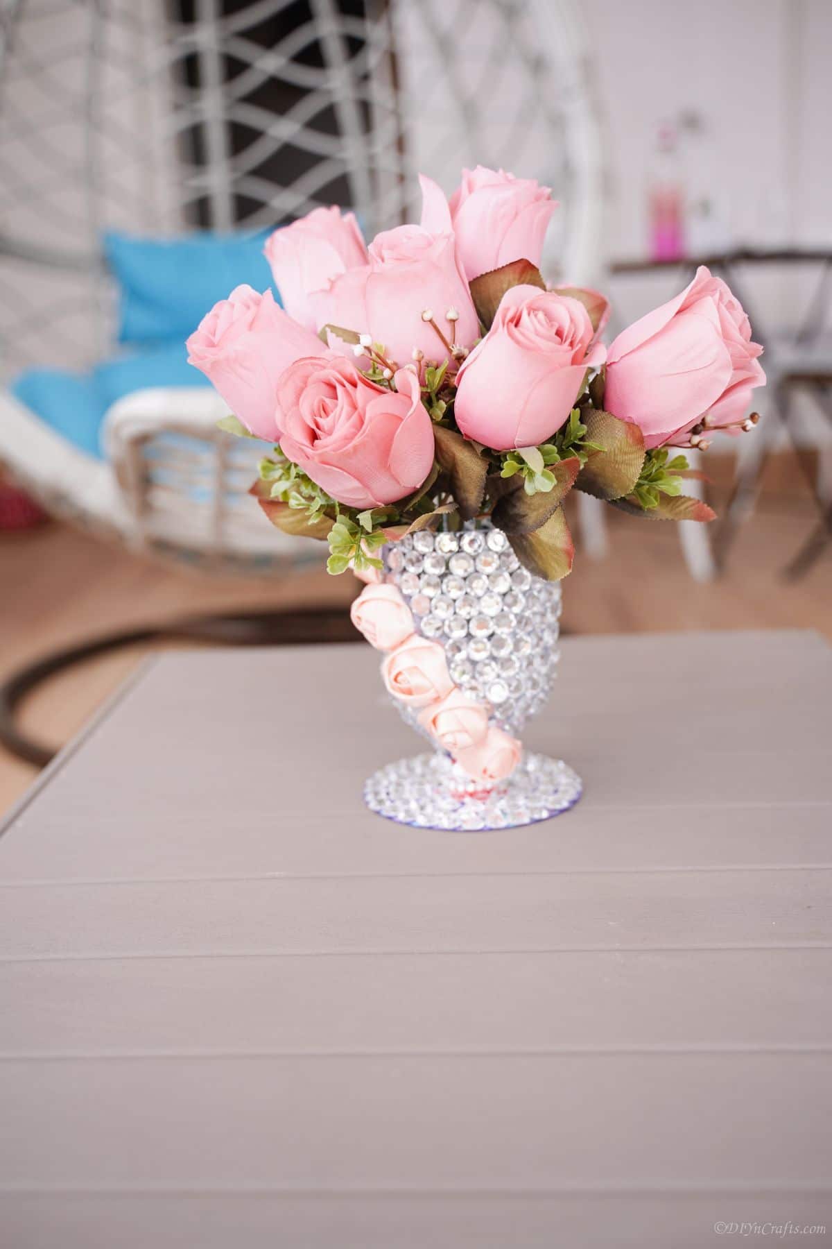 rhinestone vase of pink roses on gray table