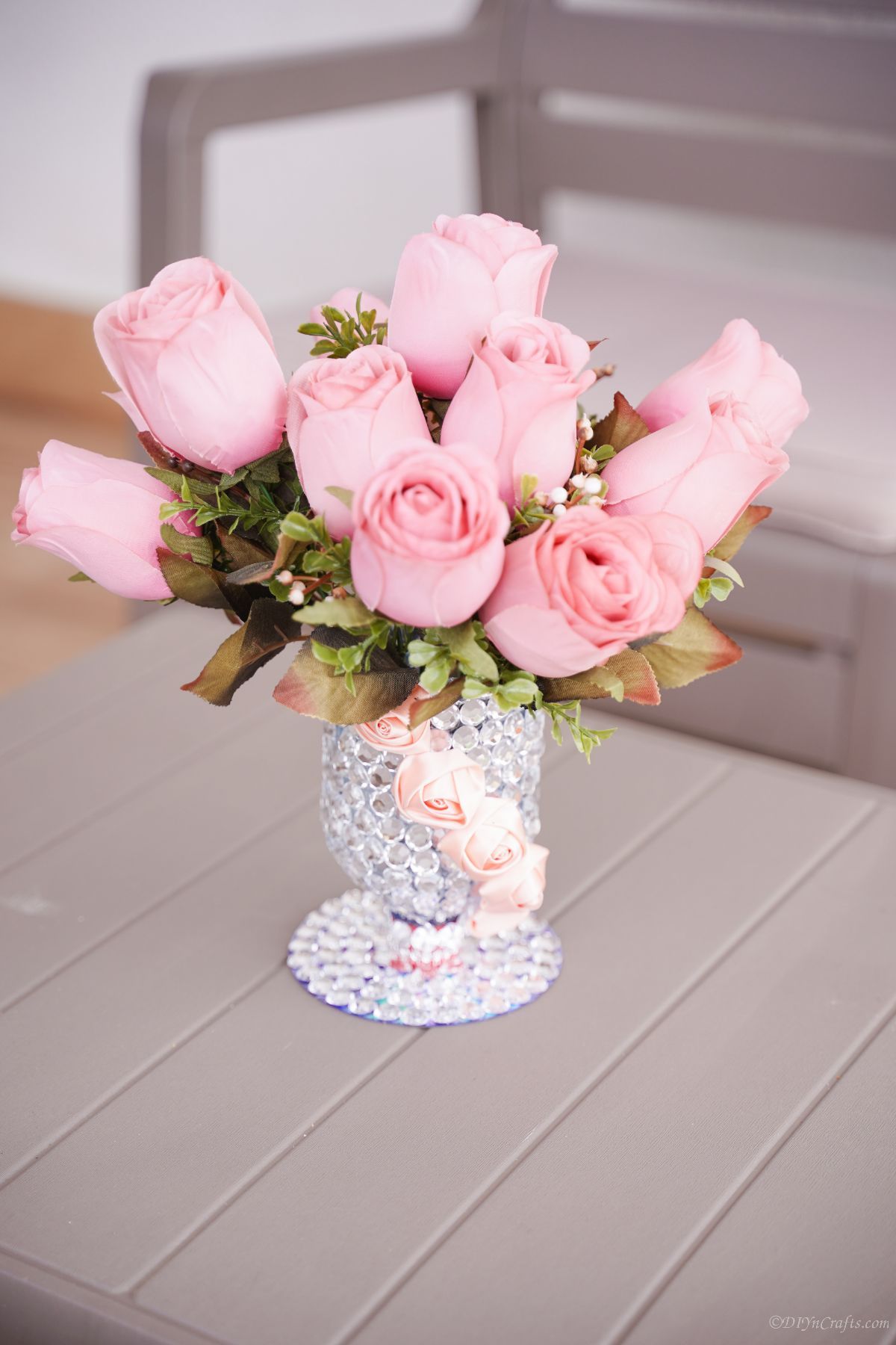 pink roses in rhinestone vase on gray table