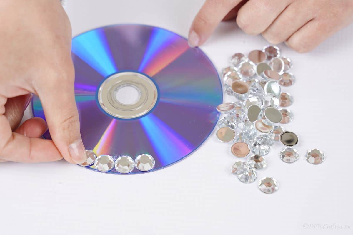 rhinestones being glued onto a CD