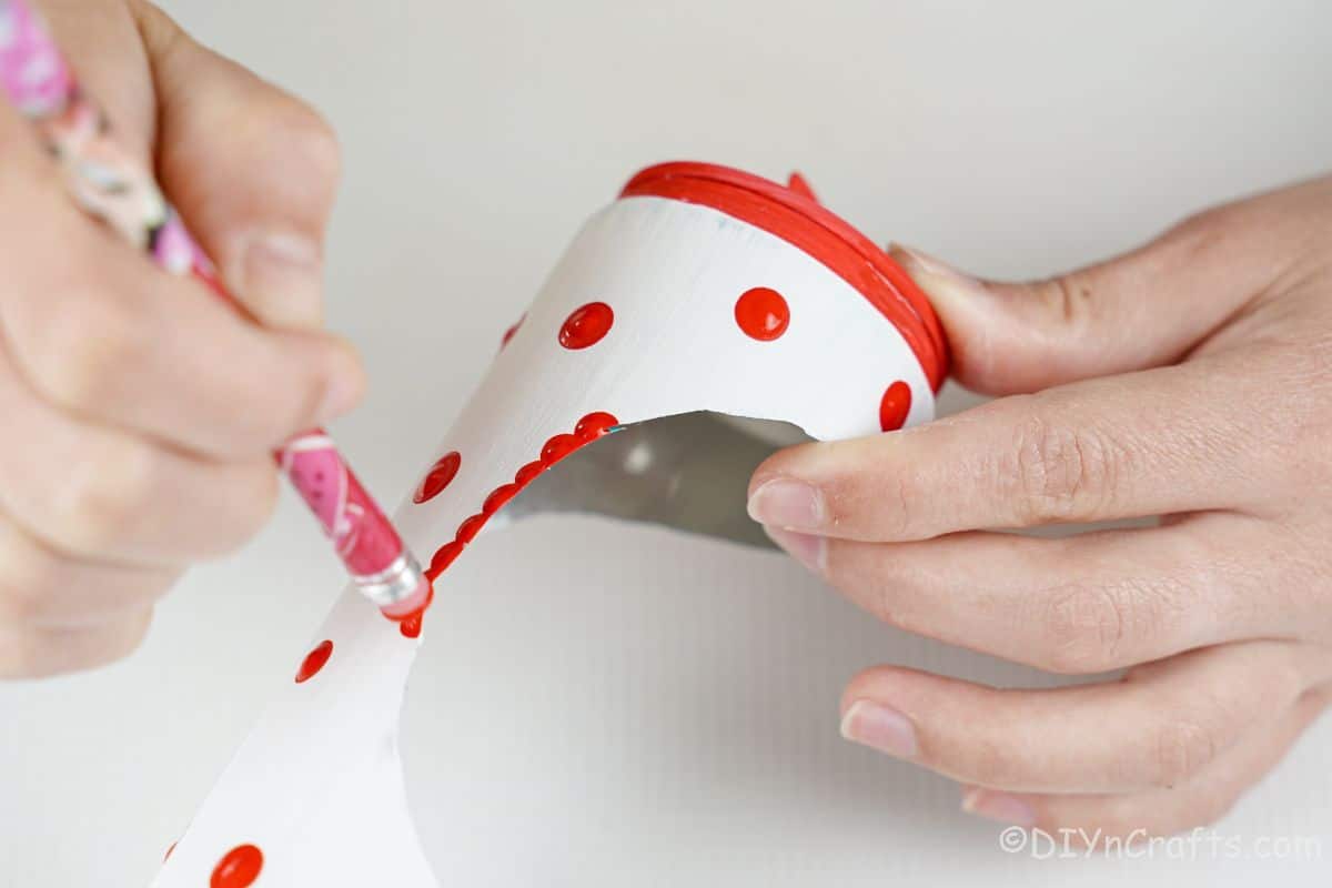 pencil eraser used as paint brush to add dots of red paint to white can