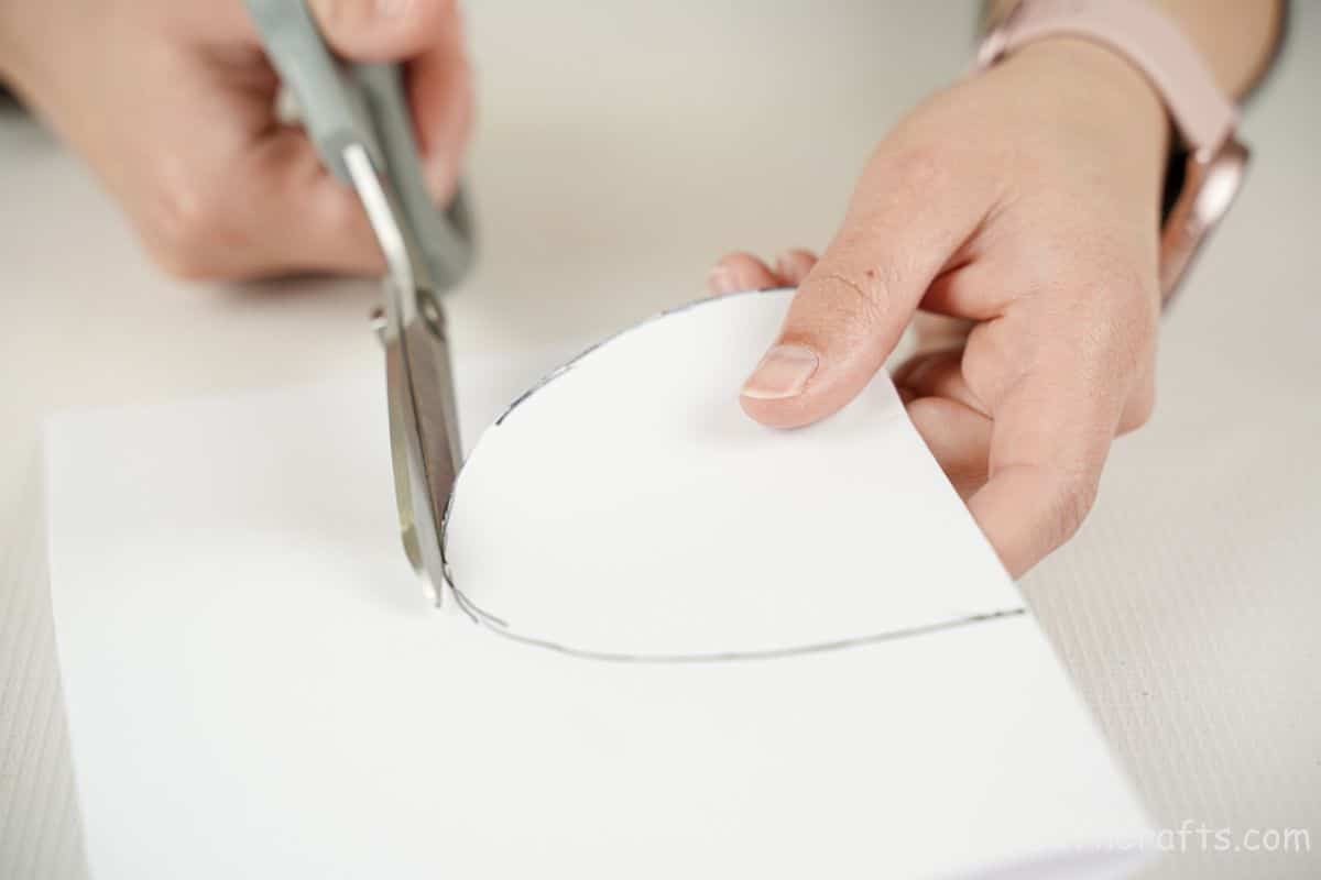 hand cutting white paper with gray scissors