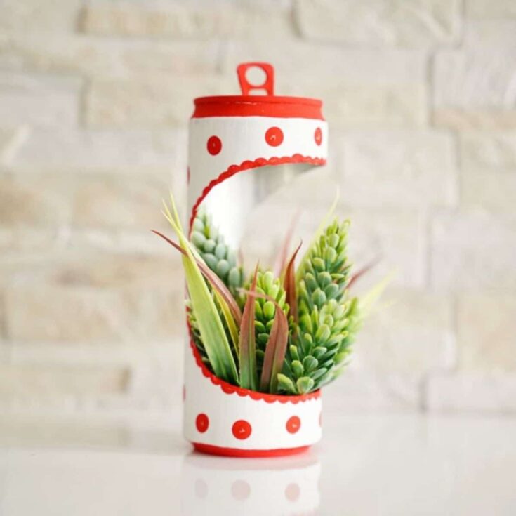 red and white soda can planter by cream brick wall
