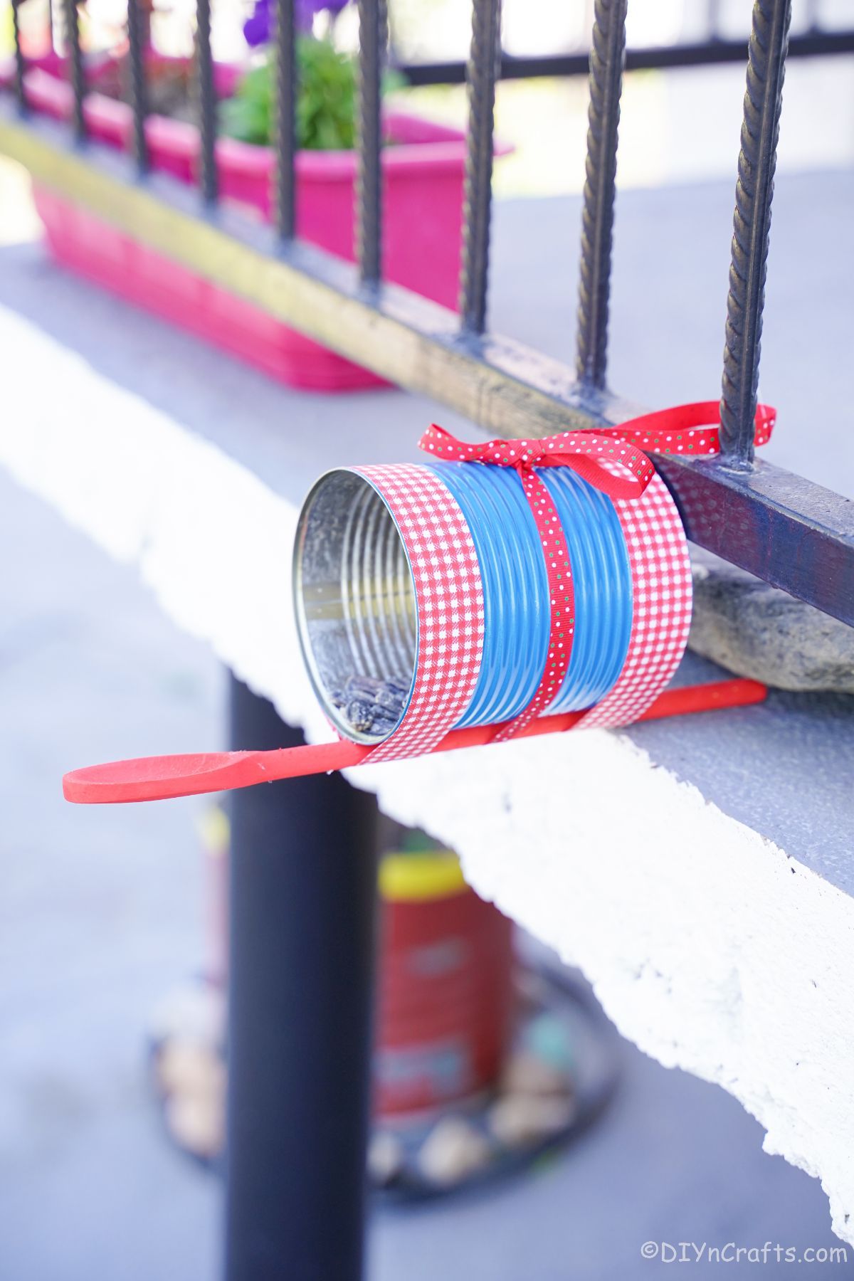 bird feeder made of a painted tin can on edge of porch