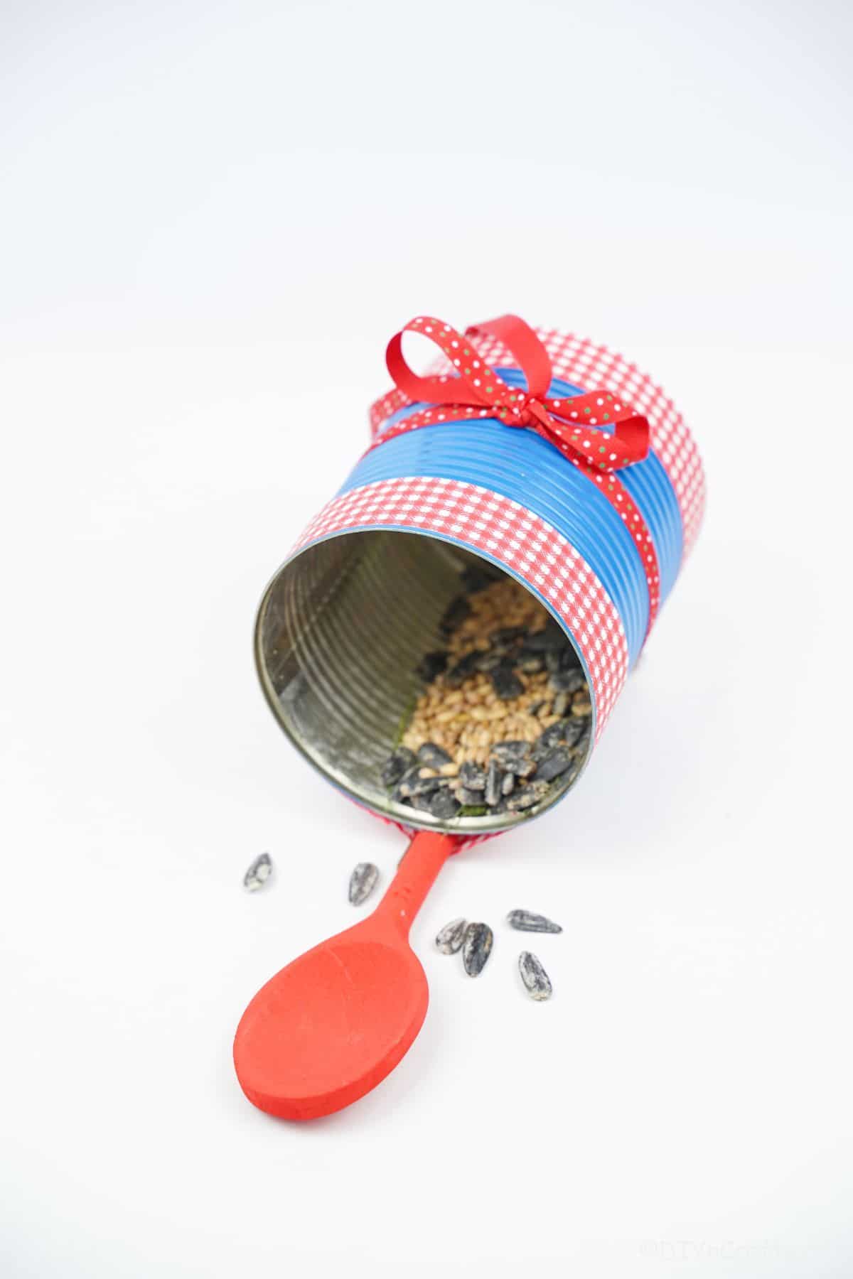 red and blue tin can bird feeder on white table
