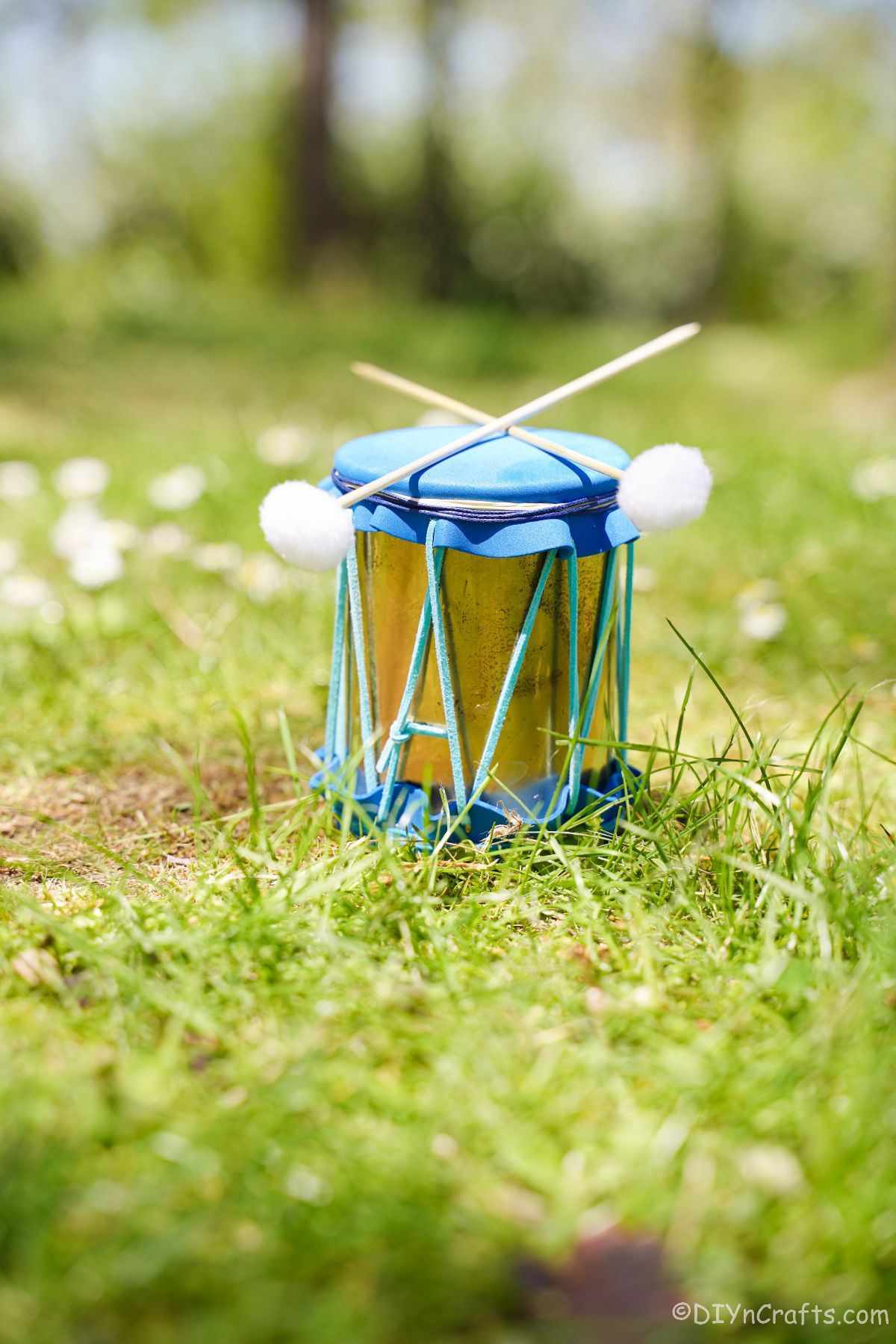 gold and blue mini drum with sticks on grass