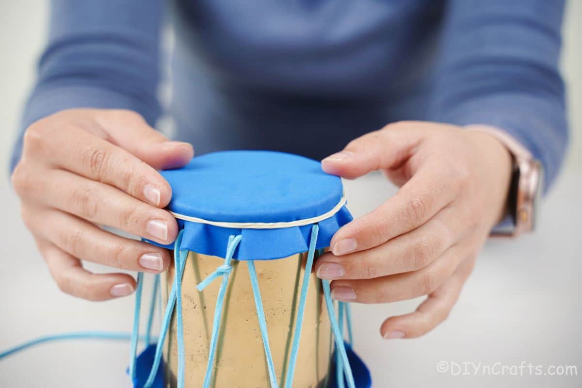hand adding rubber band on top of drum
