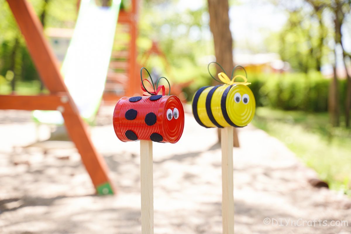 ladybug and bee garden stakes in front of swingset