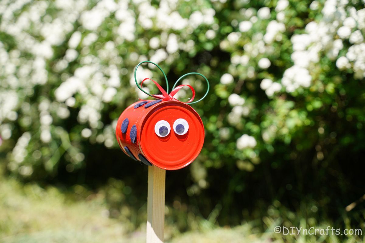 red and black tin can ladybug on garden stake