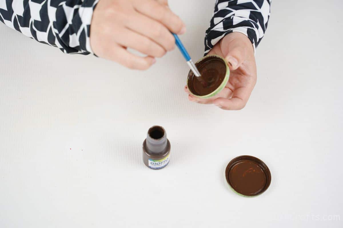 hand painting the inside of bottle caps brown