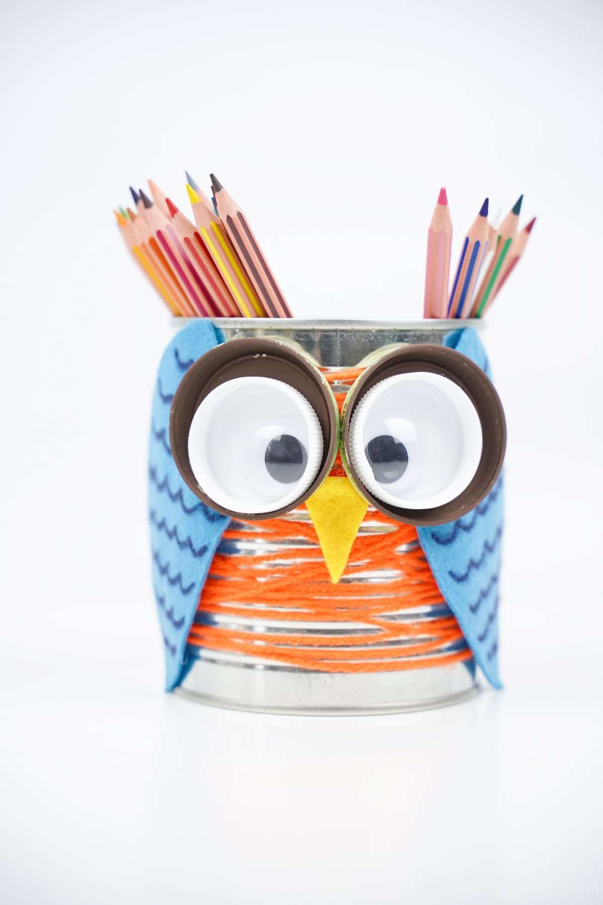 tin can owl pencil holder filled with colored pencils on white table