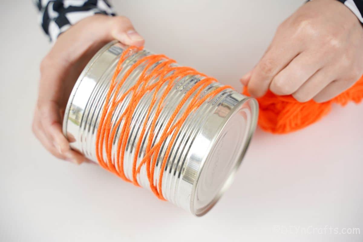 orange yarn being wrapped around tin can