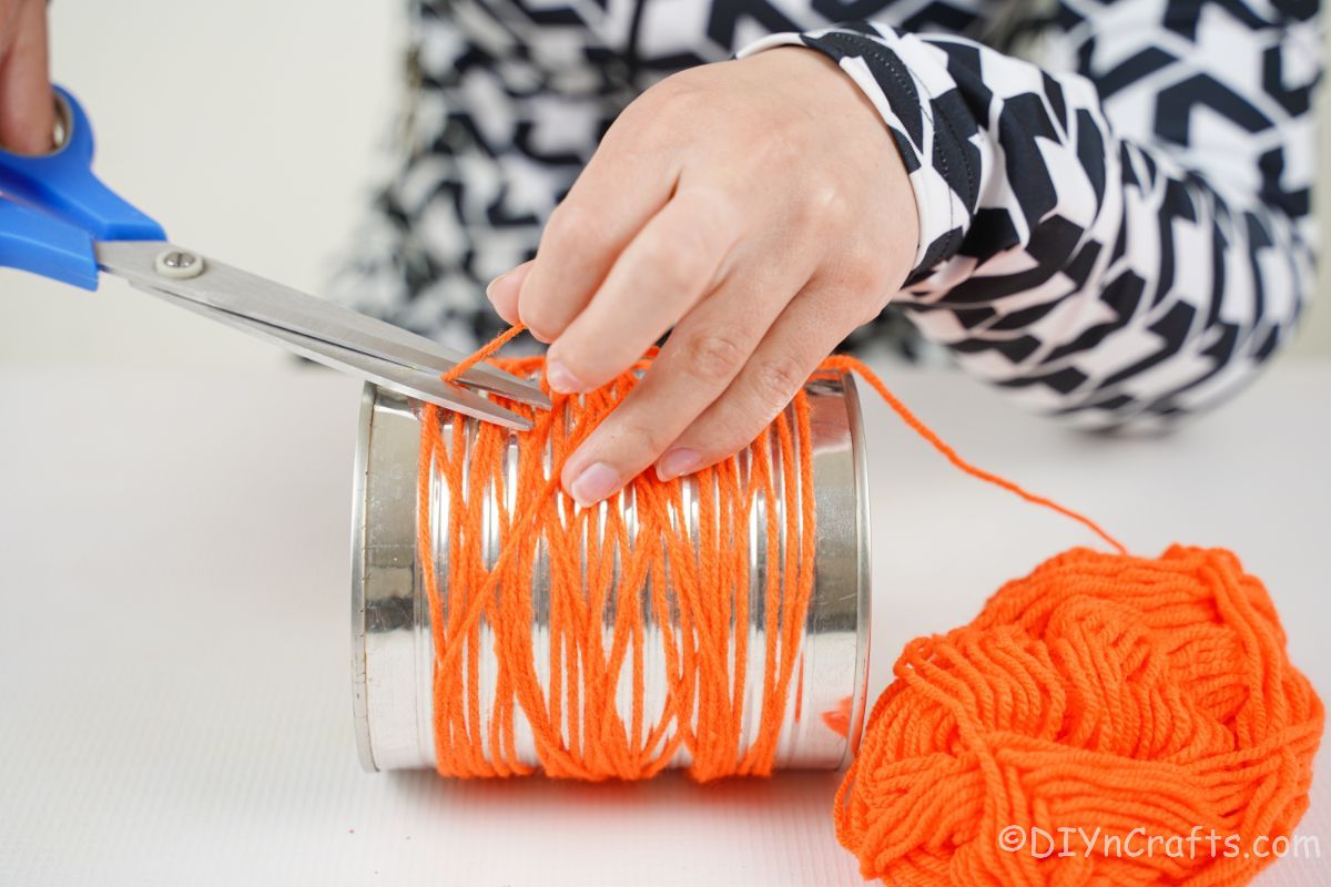 orange yarn being cut on top of tin can