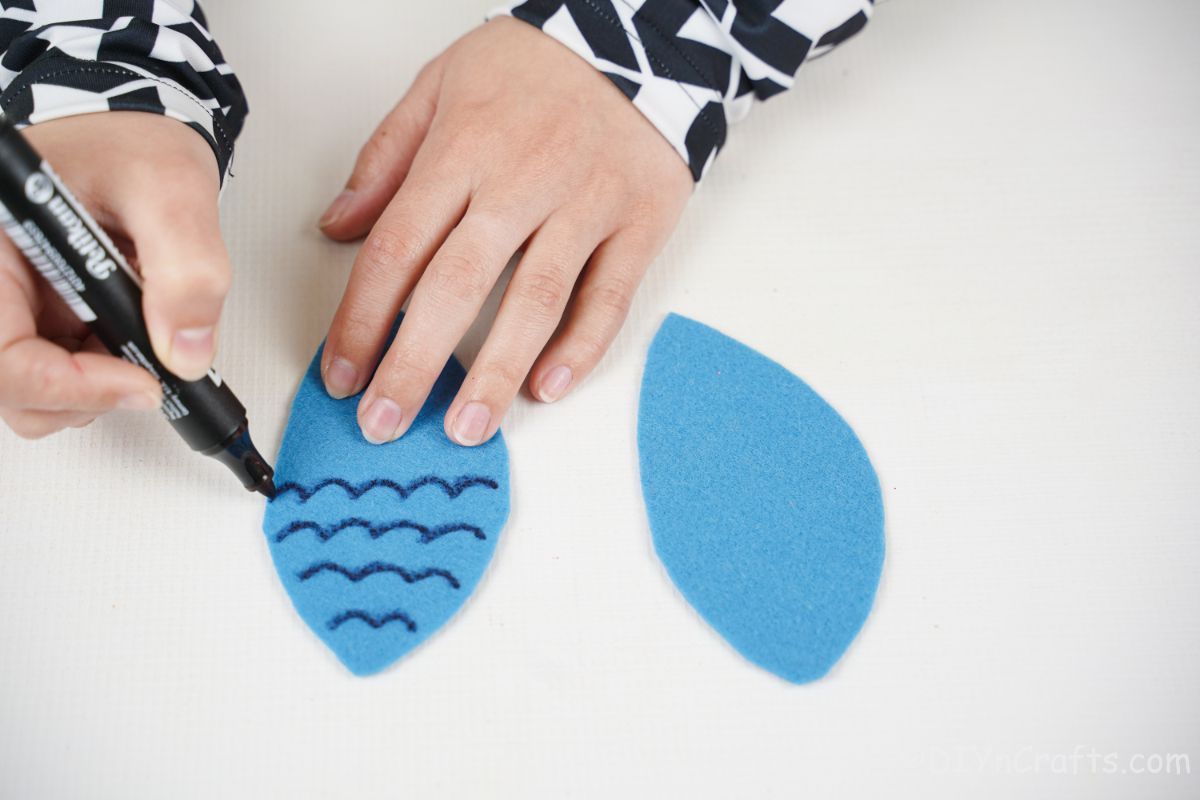 hand drawing feathers on blue owl wings for craft