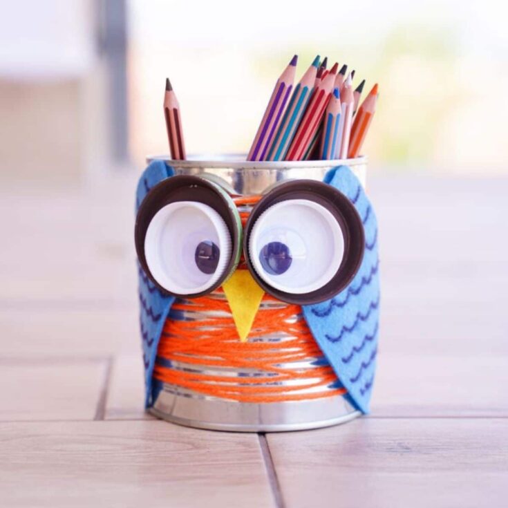tin can owl with colored pencils on floor