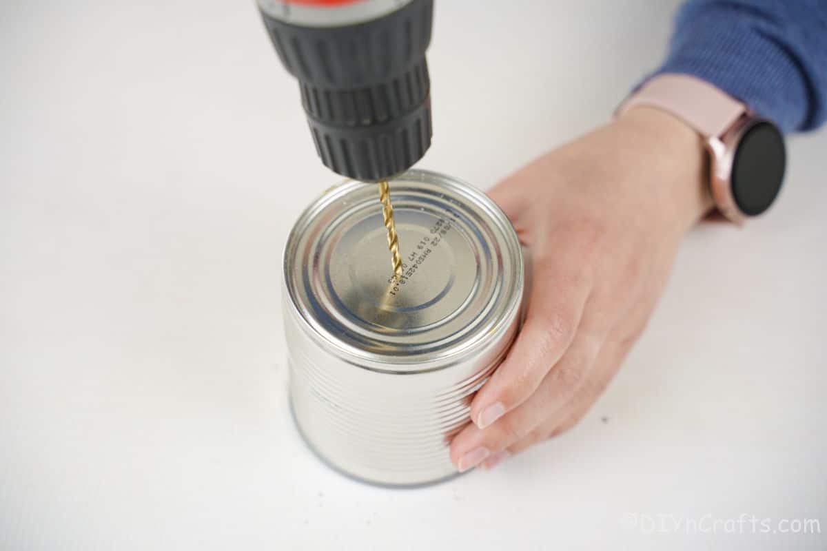 drill held above tin can on white table