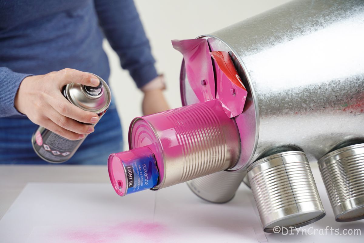 lady spraying tin cans pink
