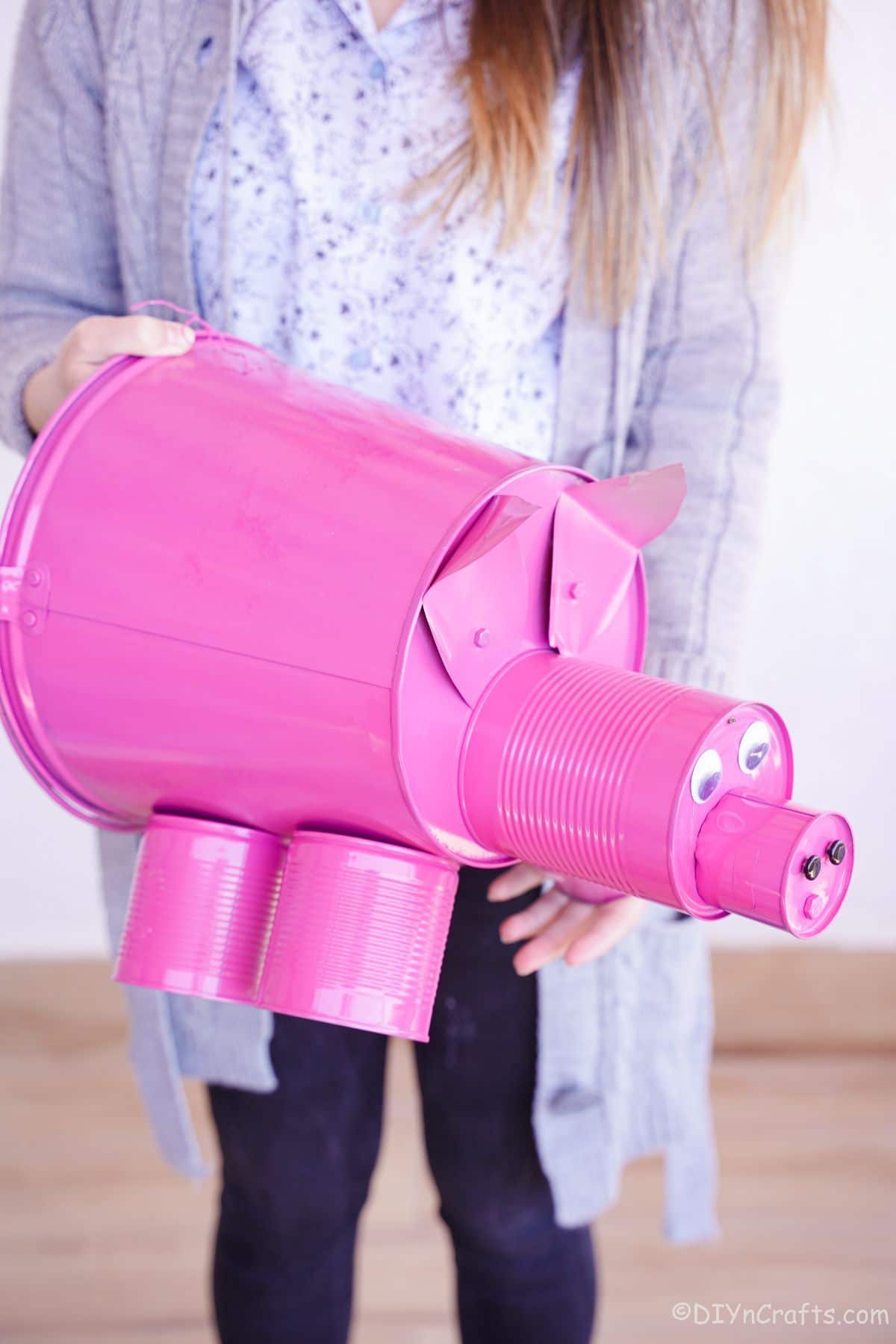 woman in jeans and sweater holding pink bucket pig decoration