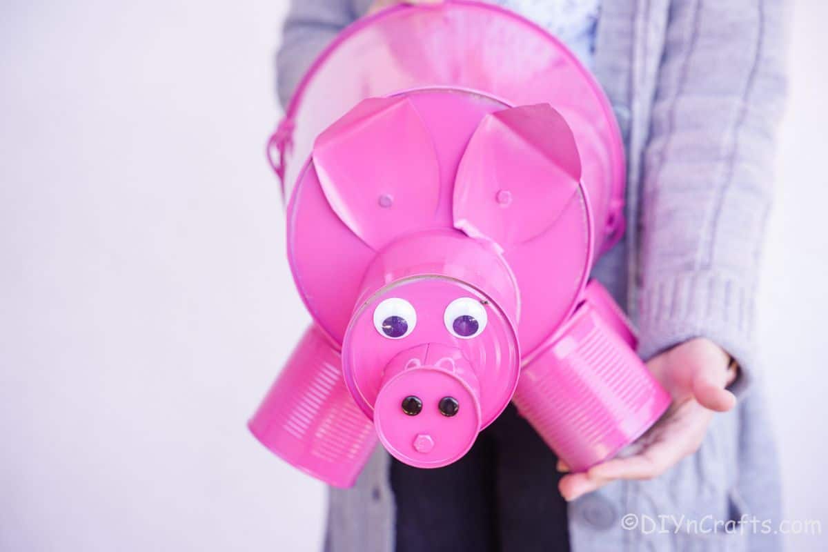 pink painted tin can and bucket pig held by a woman