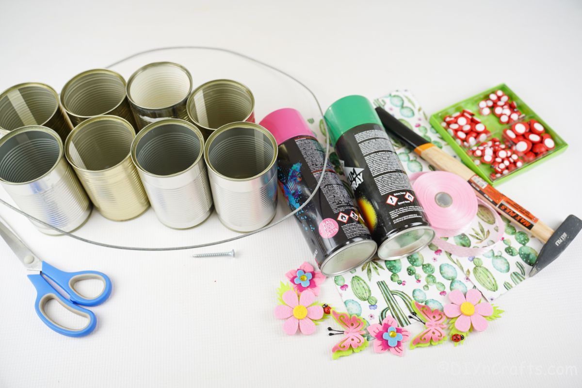 tin cans spray paint and scrapbook paper on white table