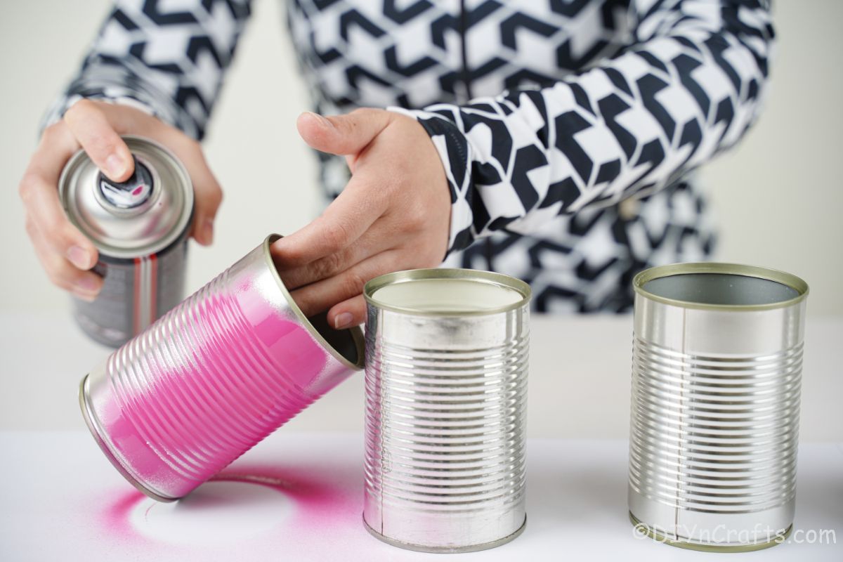 hand spraying tin cans pink
