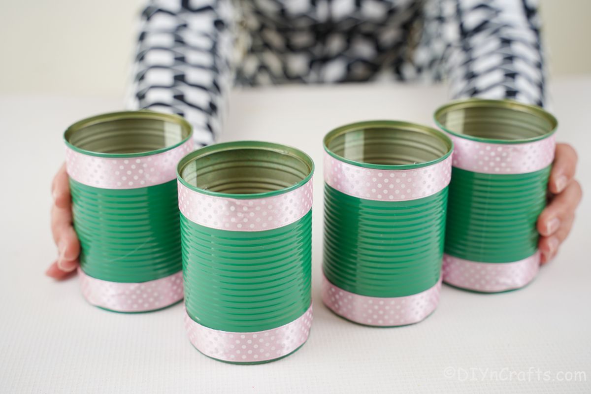 green tin cans with ribbon stacked on white table