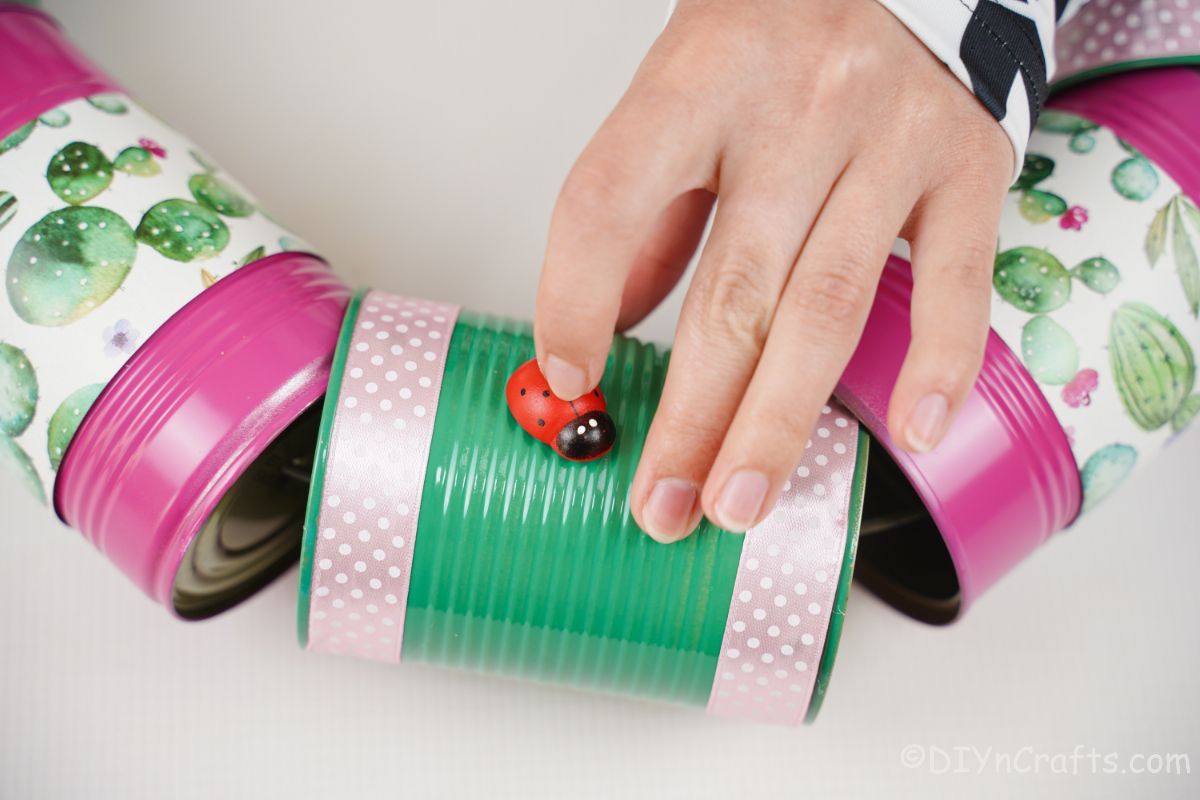 hand holding fake ladybug on green tin can
