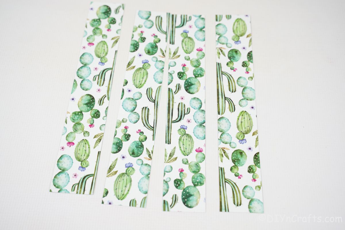 four strips of white and green cactus scrapbook paper on white table