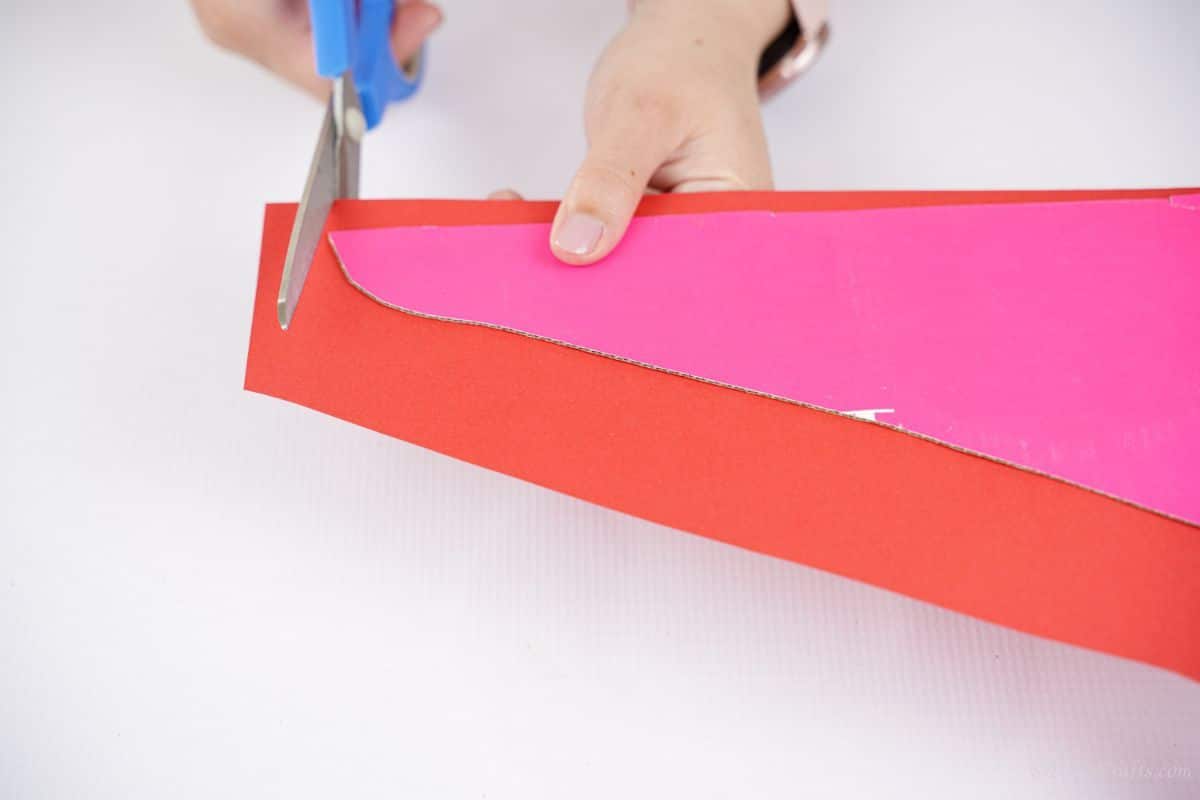 hand cutting red paper to fit cardboard wing