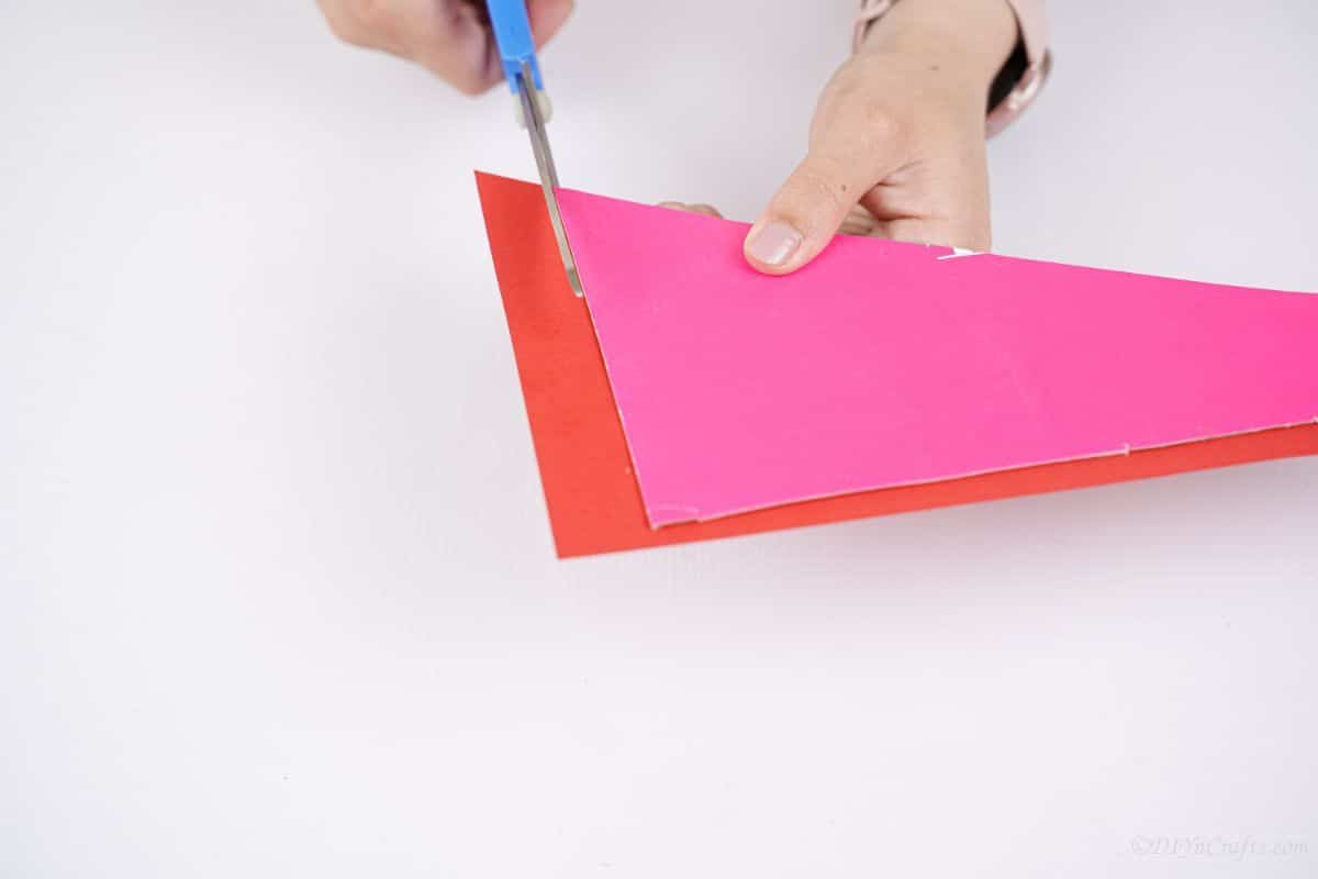 hand cutting red paper off cardboard wing