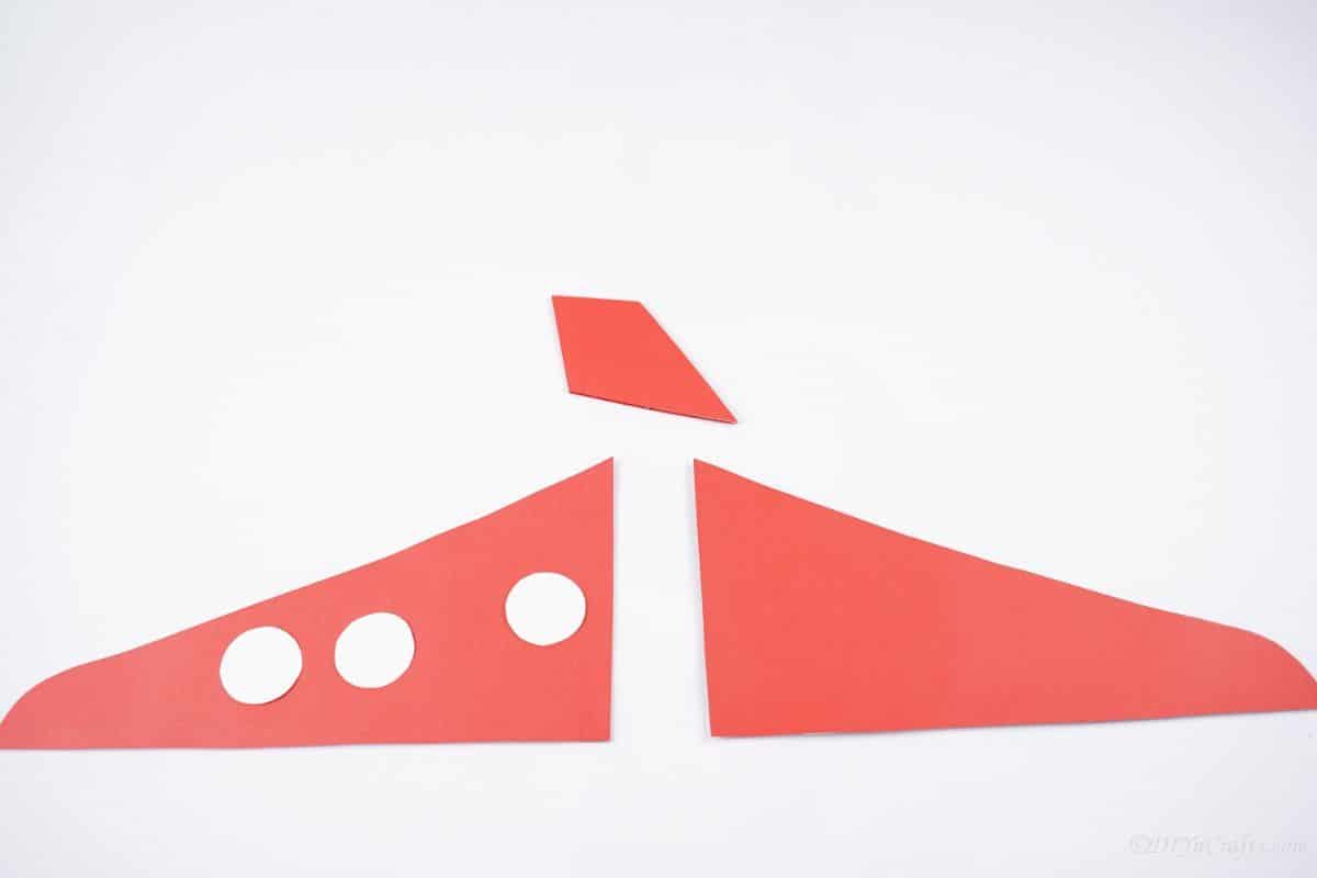 two red wings and red rudder on white table with three white dots